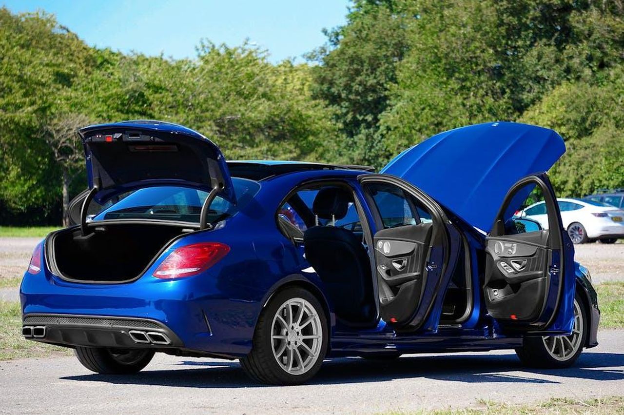 AMG_e_il_futuro_del_C63_un_cambio_radicale_qQAFxJfPIY - Veicoli24 Source: Mike Bird - pexels - A sleek blue Mercedes-Benz AMG C63 with doors and trunk open in a sunlit parking lot.
