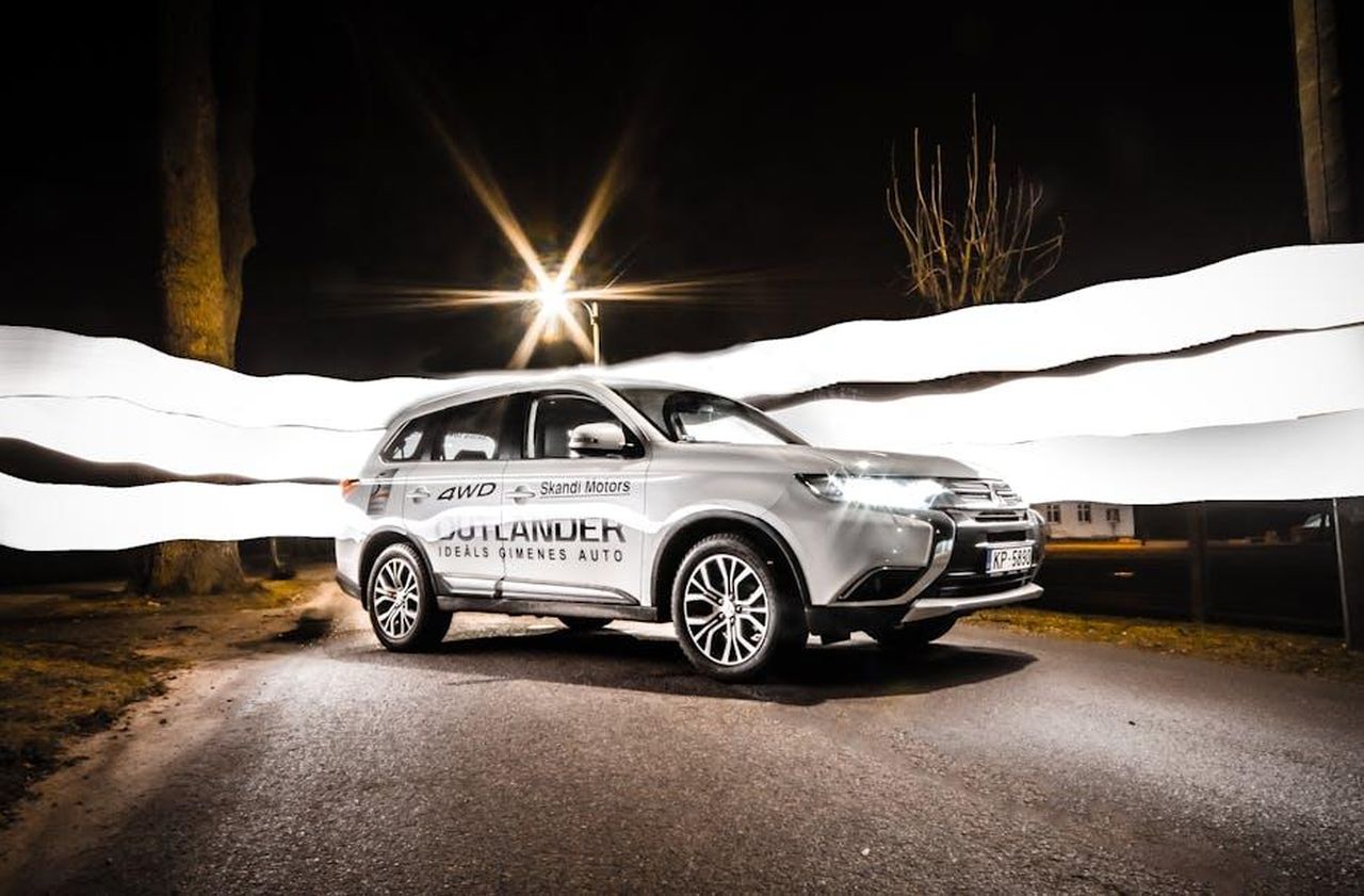 Aggiornamenti_per_la_gamma_Outlander_2025_PGSSWFxgRX - Veicoli24 Source: Toms Svilans - pexels - Mitsubishi Outlander on street with light trails at night, showcasing vehicle's sleek design.