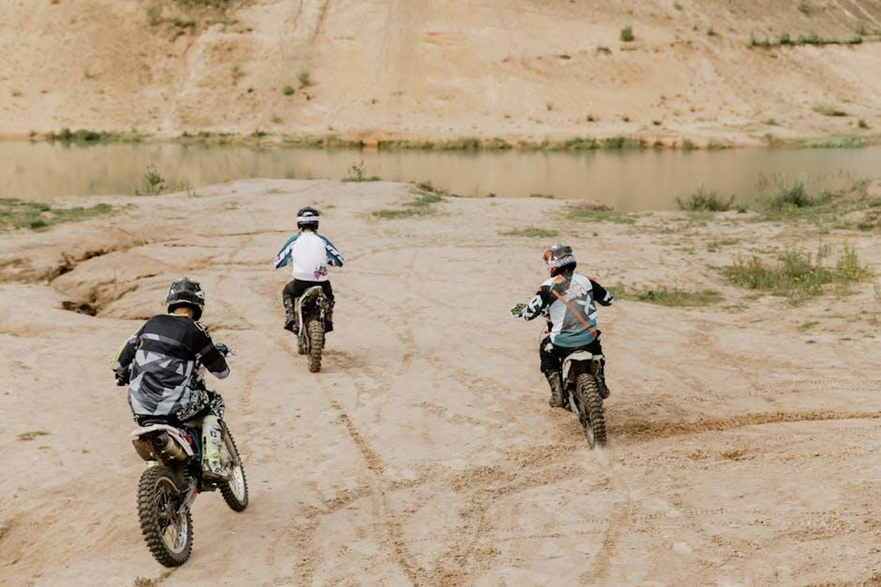 Altre_piste_in_vendita_NbzLZ4mtyf - Veicoli24 Source: cottonbro studio - pexels - Three motocross riders navigate sandy terrain near a waterbody, showcasing thrilling off-road adventure.