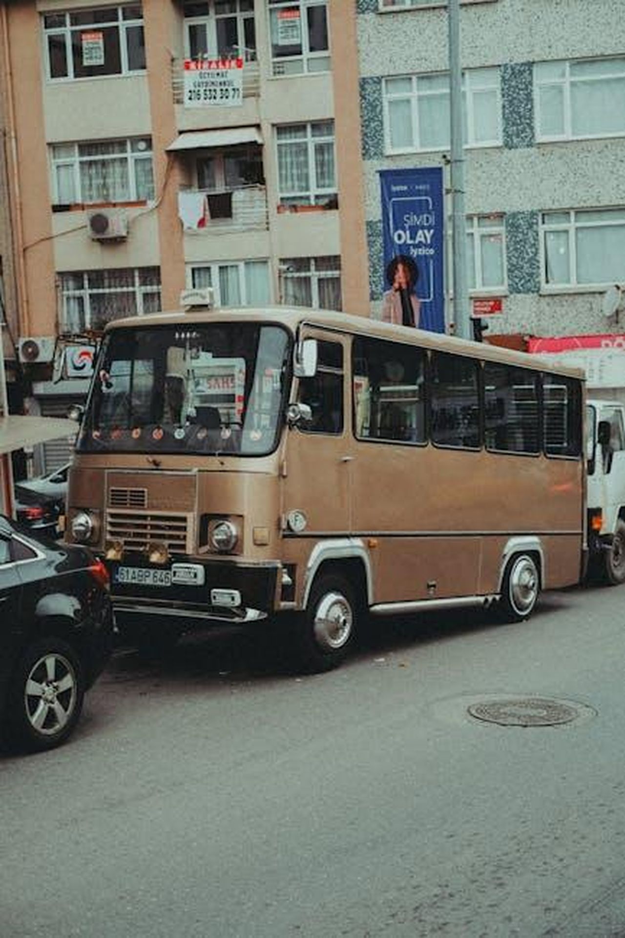 Aumento_delle_consegne_di_minibus_XO2S3ngQy4 - Veicoli24 Source: we packo - pexels - A vintage minibus parked on a busy Istanbul street, surrounded by urban buildings.