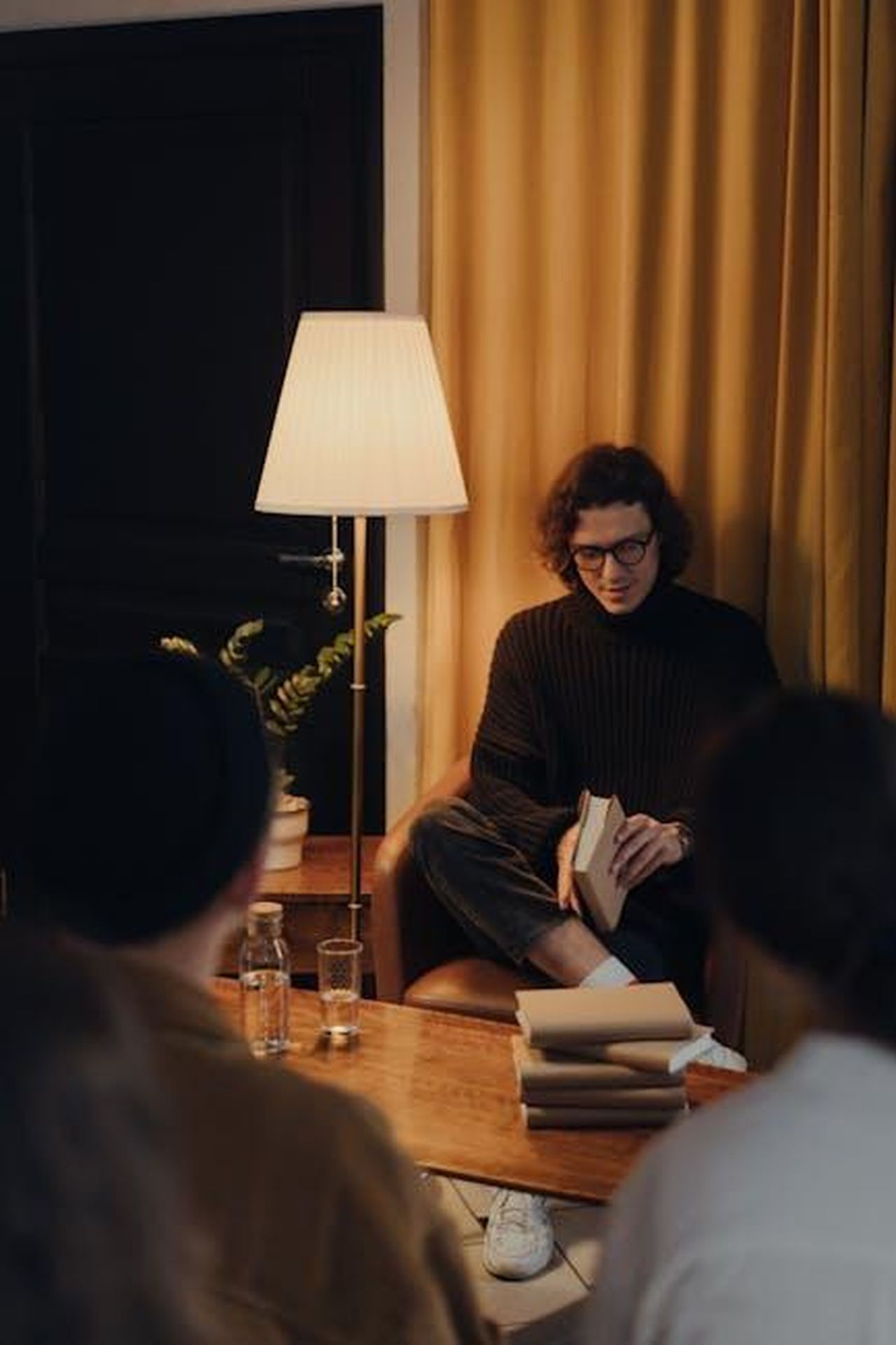 Autore_cubriVxKO3 - Veicoli24 Source: cottonbro studio - pexels - A man reads a book to a small group in a cozy, warmly lit bookstore setting.