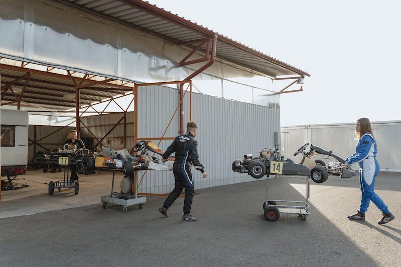 BMW_Motorrad_Motorsport_si_riorganizza_PYyuisgdVc - Veicoli24 Source: Tima Miroshnichenko - pexels - Teenagers in racing suits preparing go-karts for a race in a garage setting.