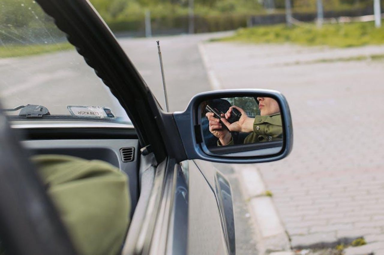 Camden_e_Islington_seguono_Haringey_ML40W3yXx4 - Veicoli24 Source: KoolShooters - pexels - A person with a gun captured in the car's side mirror, suggesting a mysterious scenario.