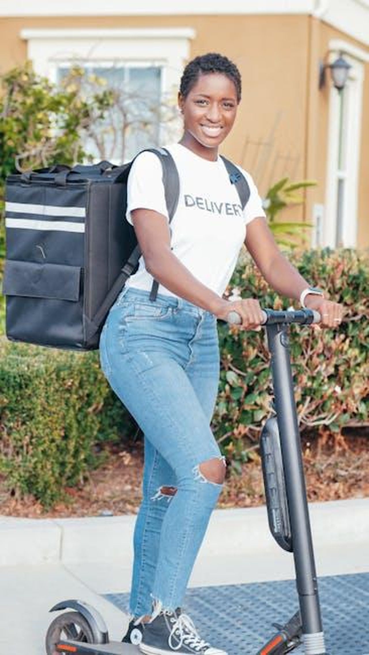 Caratteristiche_e_tecnologia_del_nuovo_SUV_Womrax8weB - Veicoli24 Source: Kindel Media - pexels - Smiling woman delivering packages using an electric scooter outdoors, representing modern delivery solutions.