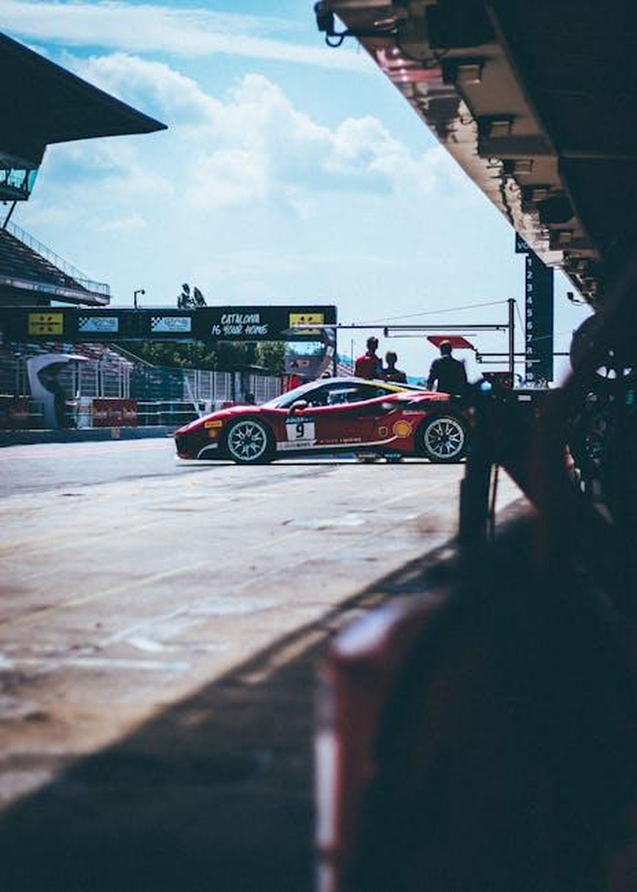 Caratteristiche_tecniche_della_SF25_u0VgBaUVhO - Veicoli24 Source: George Sultan - pexels - Red race car at Catalunya circuit pitstop, showcasing motorsport excitement and design.