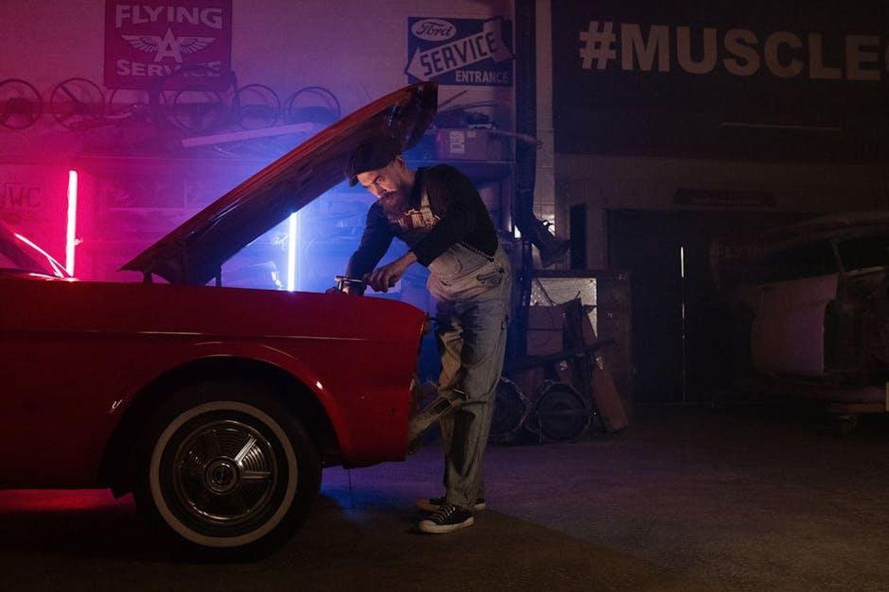 Chi__John_Davis_SKlzagV1b5 - Veicoli24 Source: cottonbro studio - pexels - A mechanic working on a vintage car in a garage with colorful neon lights.