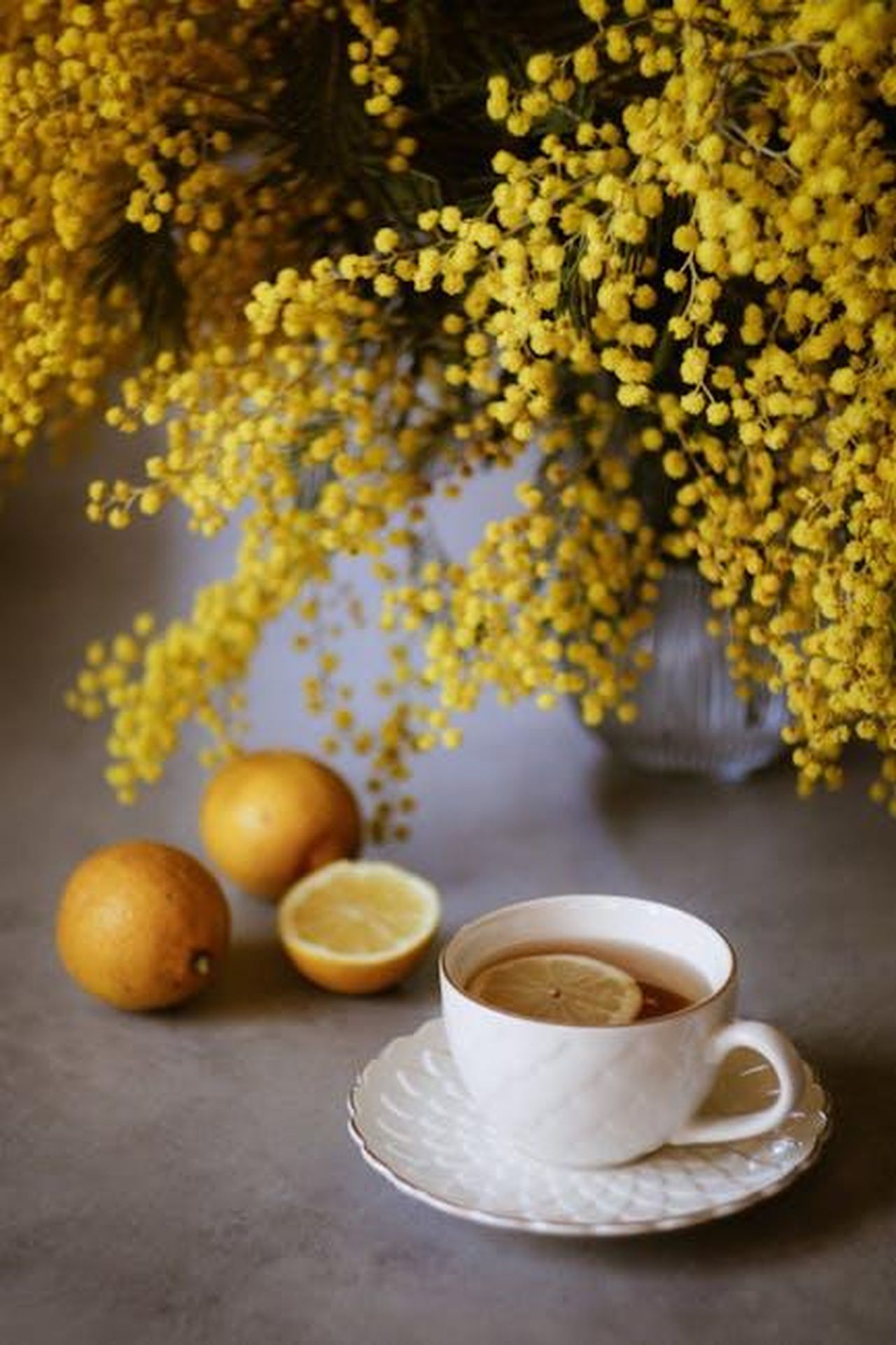 Comfort_e_qualit_della_Cadillac_CT5_2025_PJLQupCBCw - Veicoli24 Source: Nati - pexels - A warm cup of tea with lemon slices by vibrant yellow mimosa flowers.
