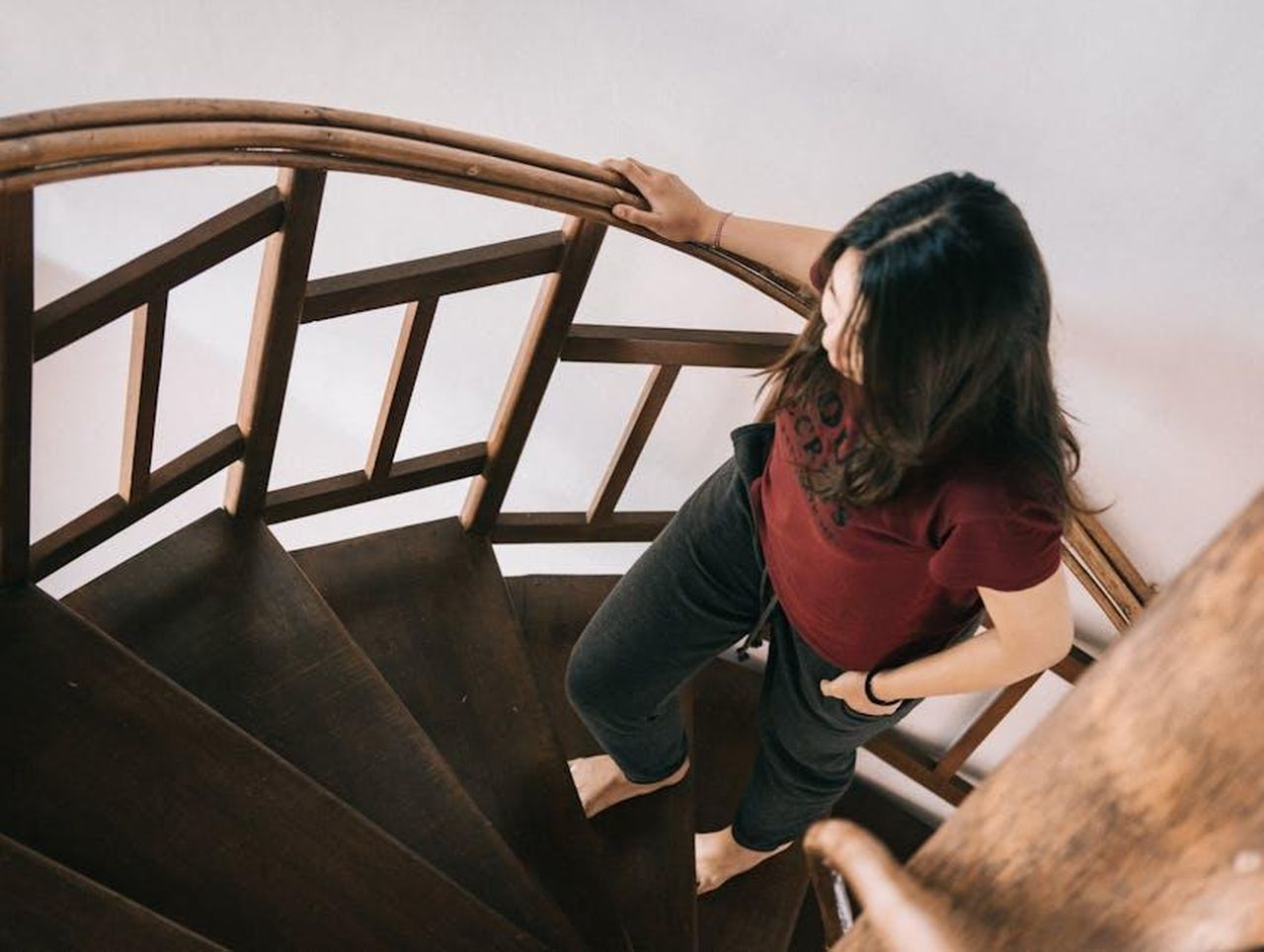 Comfort_e_qualit_della_Subaru_Ascent_2025_EJ4JkcNBOf - Veicoli24 Source: Agung Pandit Wiguna - pexels - A woman in casual attire ascends a wooden spiral staircase, viewed from above.