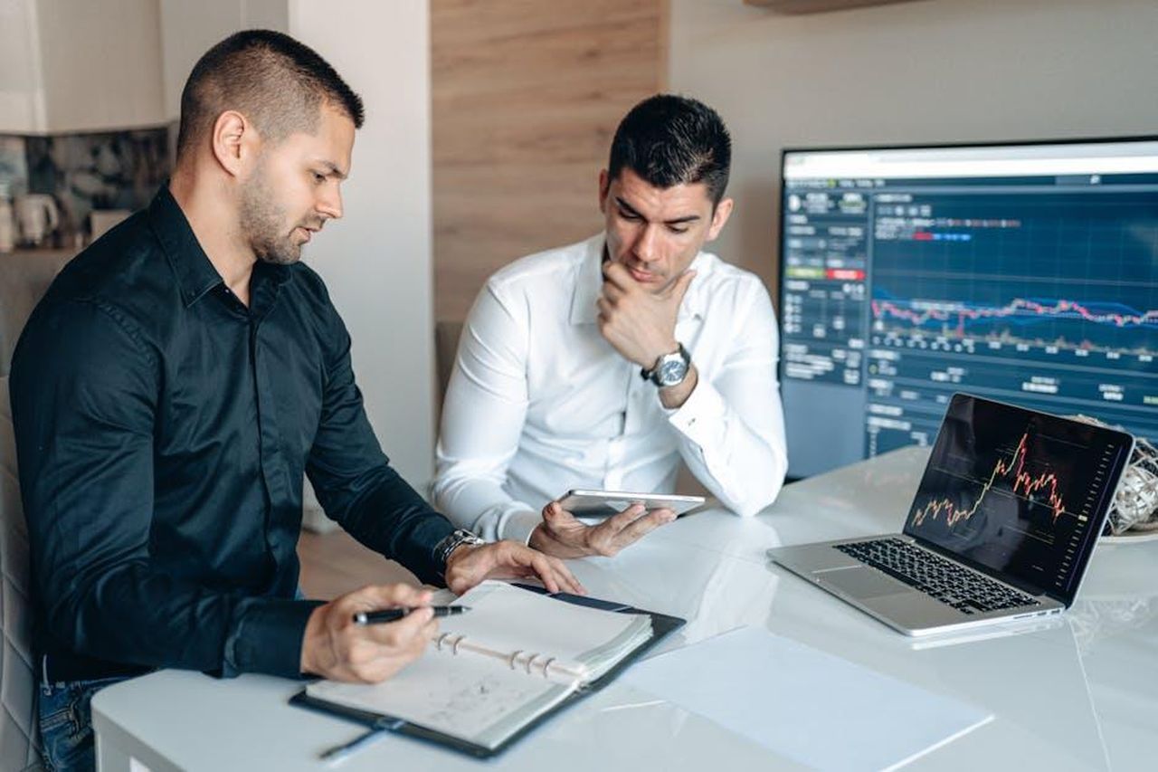 Commenti_del_portavoce_del_Piano_per_i_Furgoni_a_Zero_Emissioni_RcMWK18KCj - Veicoli24 Source: George Morina - pexels - Two businessmen discussing stock market analytics in a modern office setting.