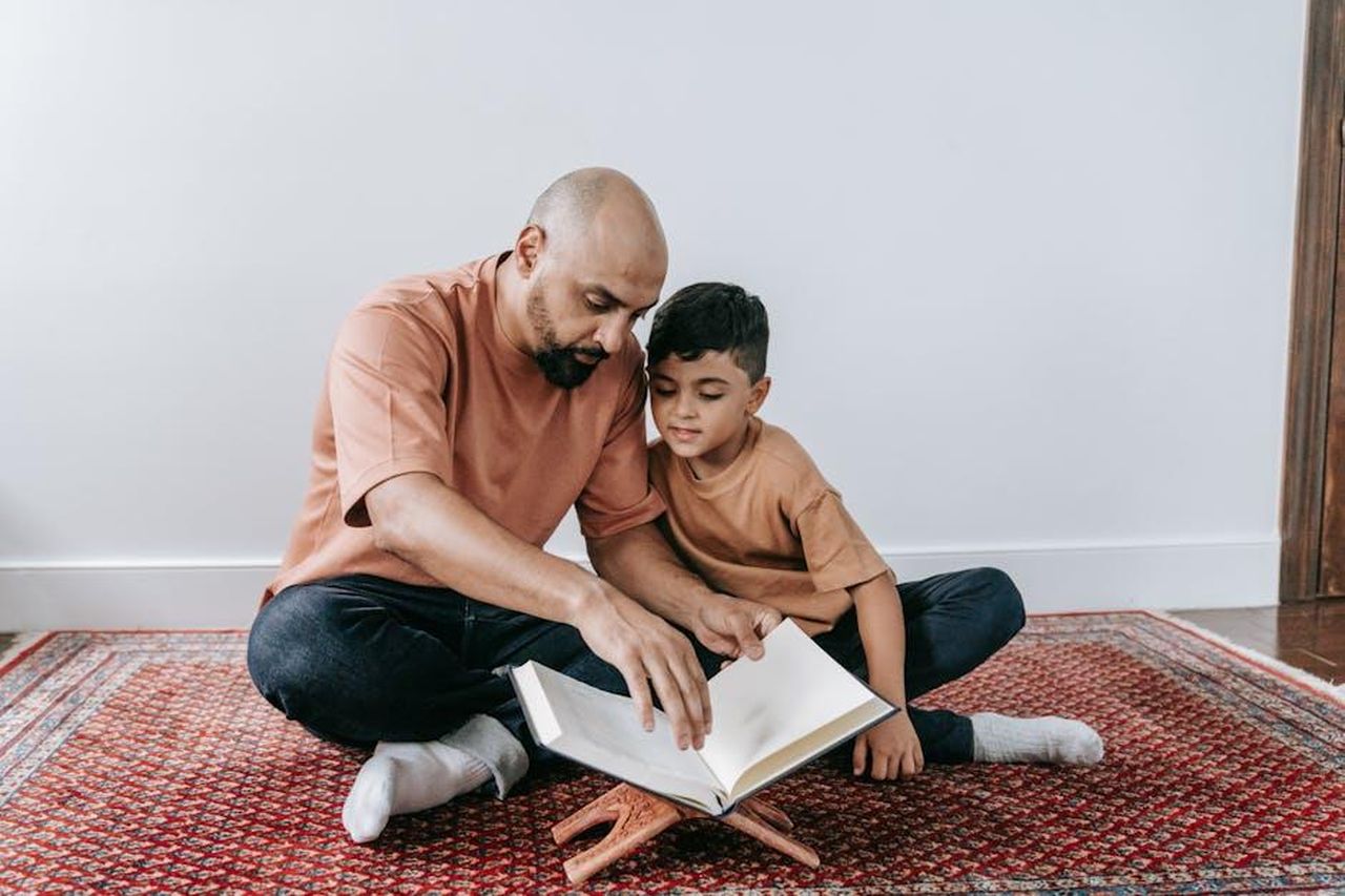 Comprendere_la_Commozione_Cerebrale_ygX6N8sc98 - Veicoli24 Source: Timur Weber - pexels - A father and son sitting on a rug, bonding over reading indoors.