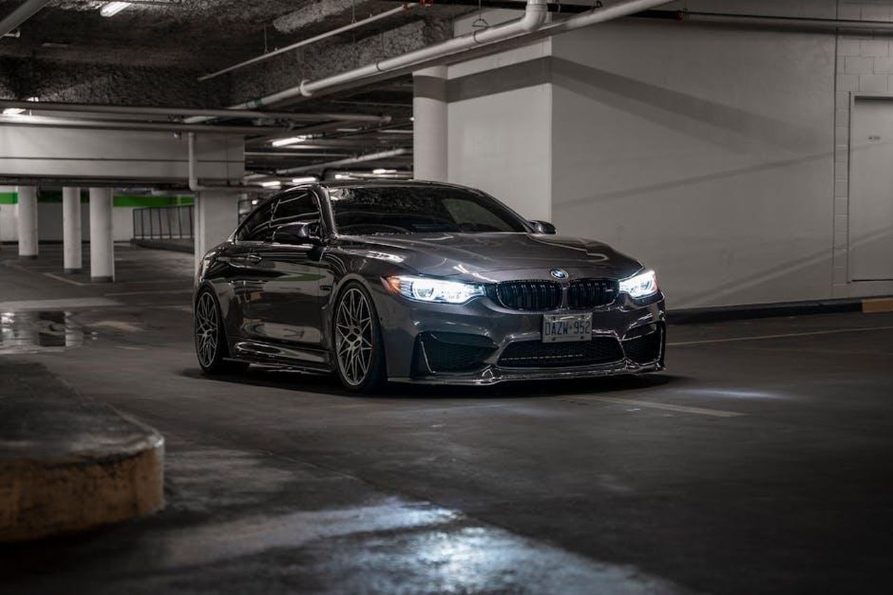 Confronto_con_la_concorrenza_ap0u1vR5vy - Veicoli24 Source: Bradley De Melo - pexels - A sleek black BMW parked in a dimly lit underground garage with illuminated headlights.