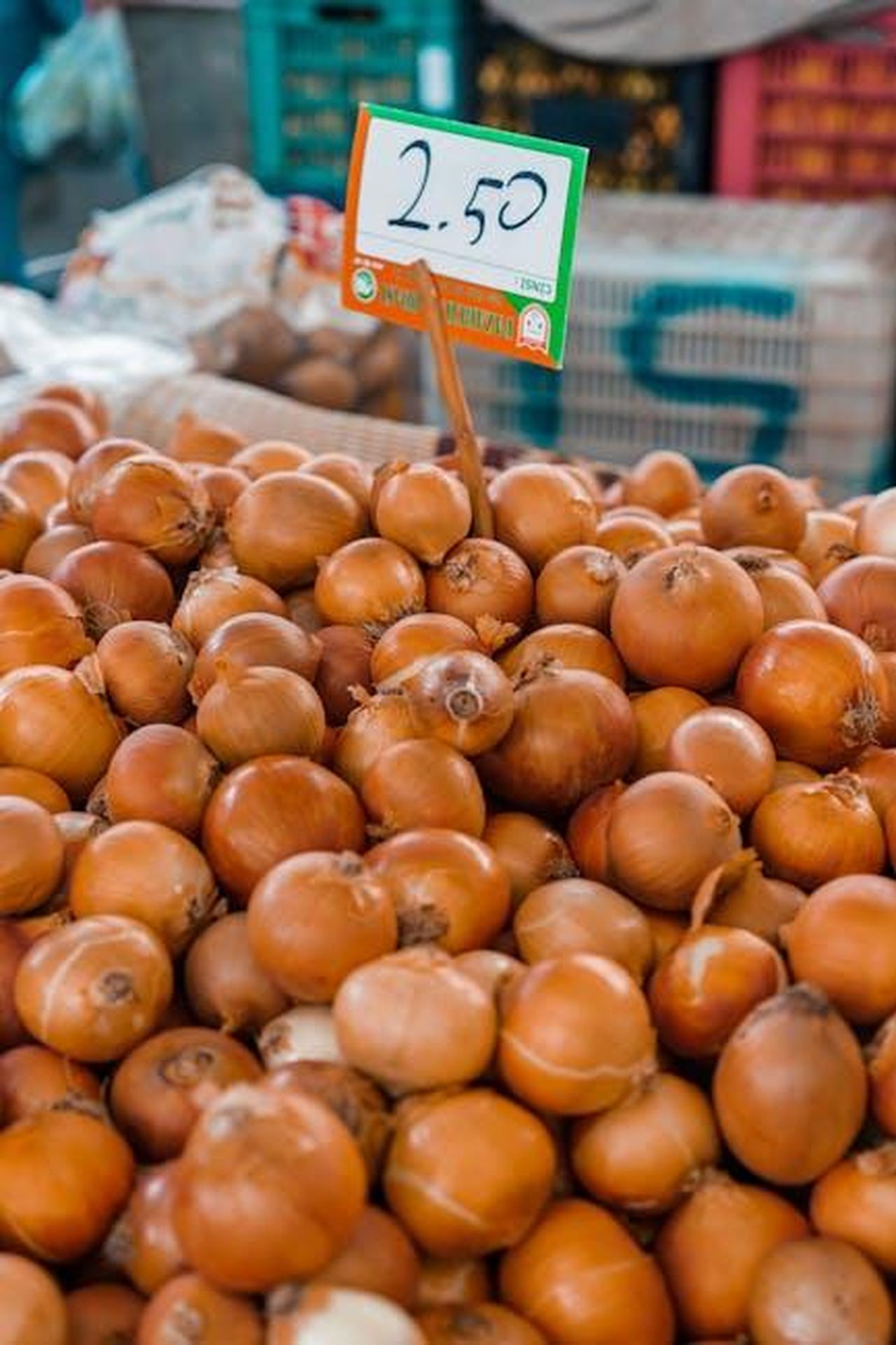 Consiglio_per_lacquisto_HOTtAqLRwr - Veicoli24 Source: Alex P - pexels - Close-up of fresh onions stacked with a price tag at a bustling outdoor market.