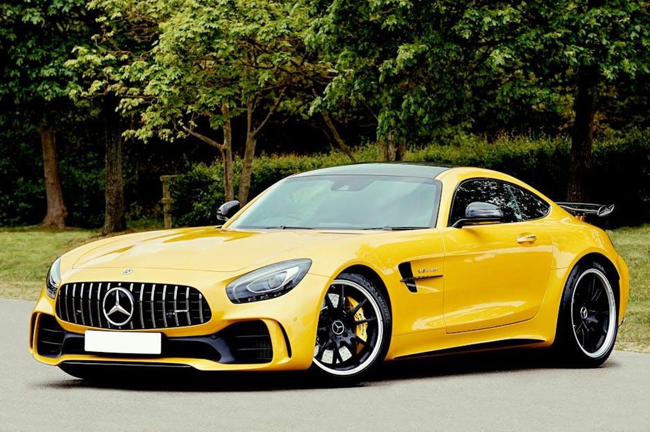 Consiglio_per_lacquisto_JwuoD1CT80 - Veicoli24 Source: Mike Bird - pexels - An elegant yellow sports car parked outdoors in a park setting, surrounded by lush greenery.