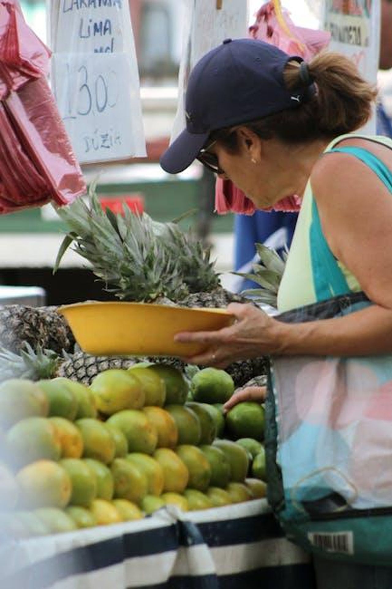Consiglio_per_lacquisto_Z8xSkihocI - Veicoli24 Source: Nanda Mends - pexels - A woman selects fresh pineapples at a vibrant outdoor market fruit stand.