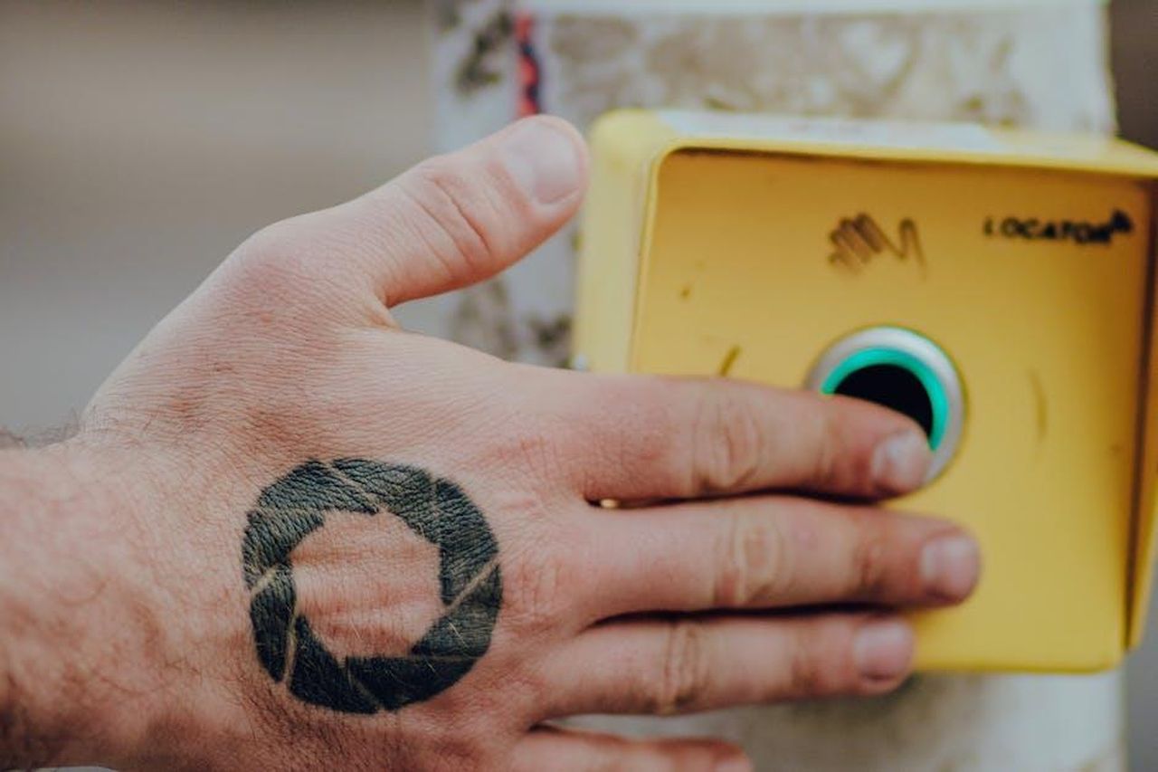 Contatti_Stampa_0tk93QY9lr - Veicoli24 Source: Grish Petrosyan - pexels - A hand with a geometric tattoo presses a yellow button outdoors. Ideal for concepts of interaction and design.