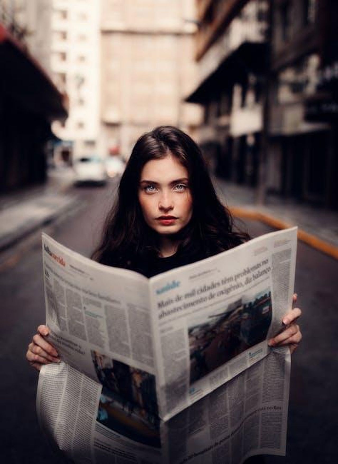 Contatti_Stampa_e_Autori_4DOH1uHvM7 - Veicoli24 Source: Dinnow - pexels - Portrait of a woman standing in an urban street holding a newspaper.