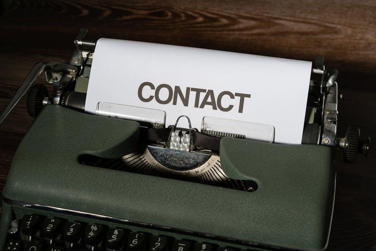 Contatto_Stampa_Zzo7F8FpJN - Veicoli24 Source: Markus Winkler - pexels - Close-up of a vintage typewriter with a white paper sheet displaying the word 'CONTACT' in bold text.