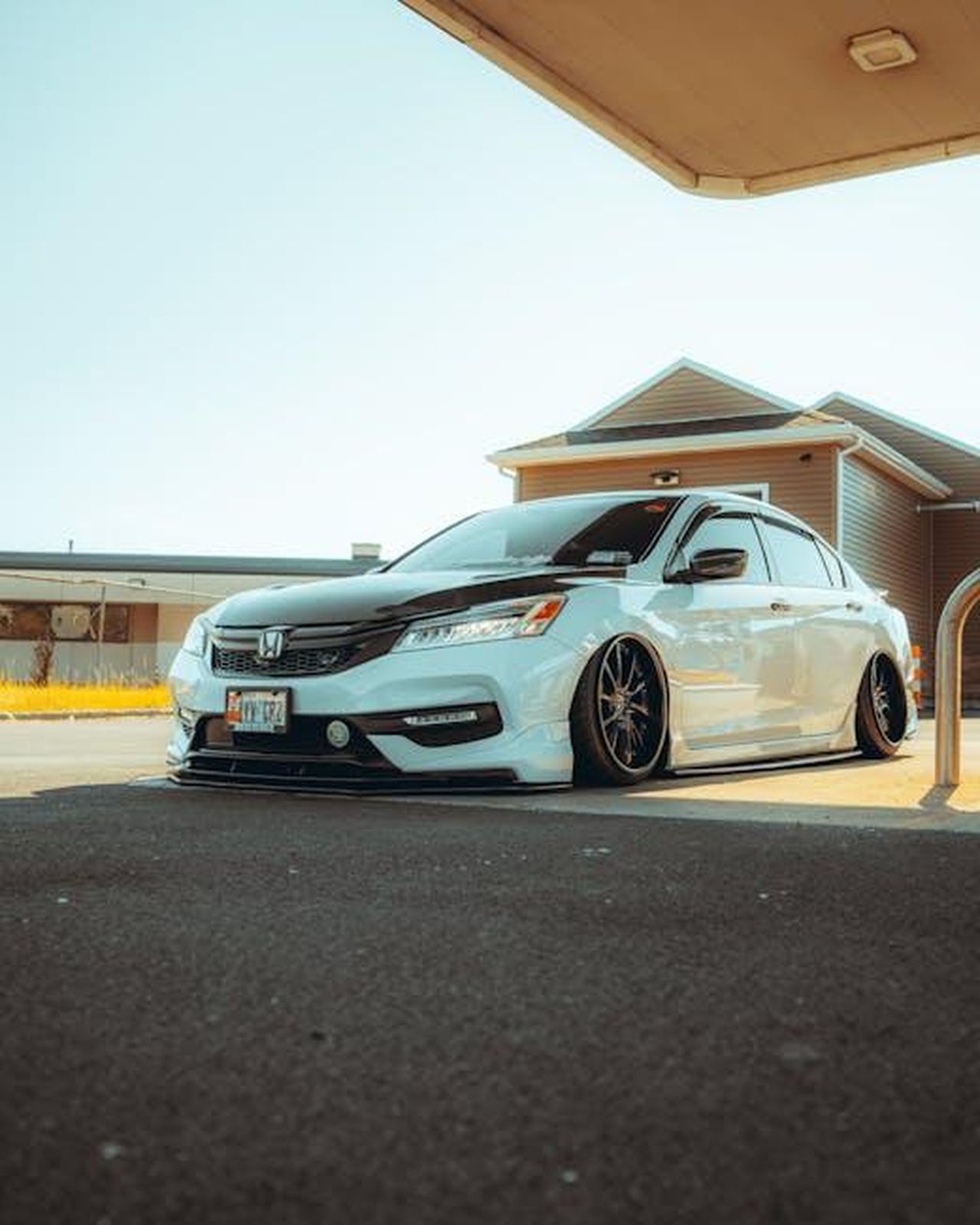 Cosa_non_ci_piace_della_Honda_Accord_2025_2xXq7uLnB8 - Veicoli24 Source: Kamshotthat - pexels - Sleek white sedan with tinted windows parked on a sunny day under a shade structure.