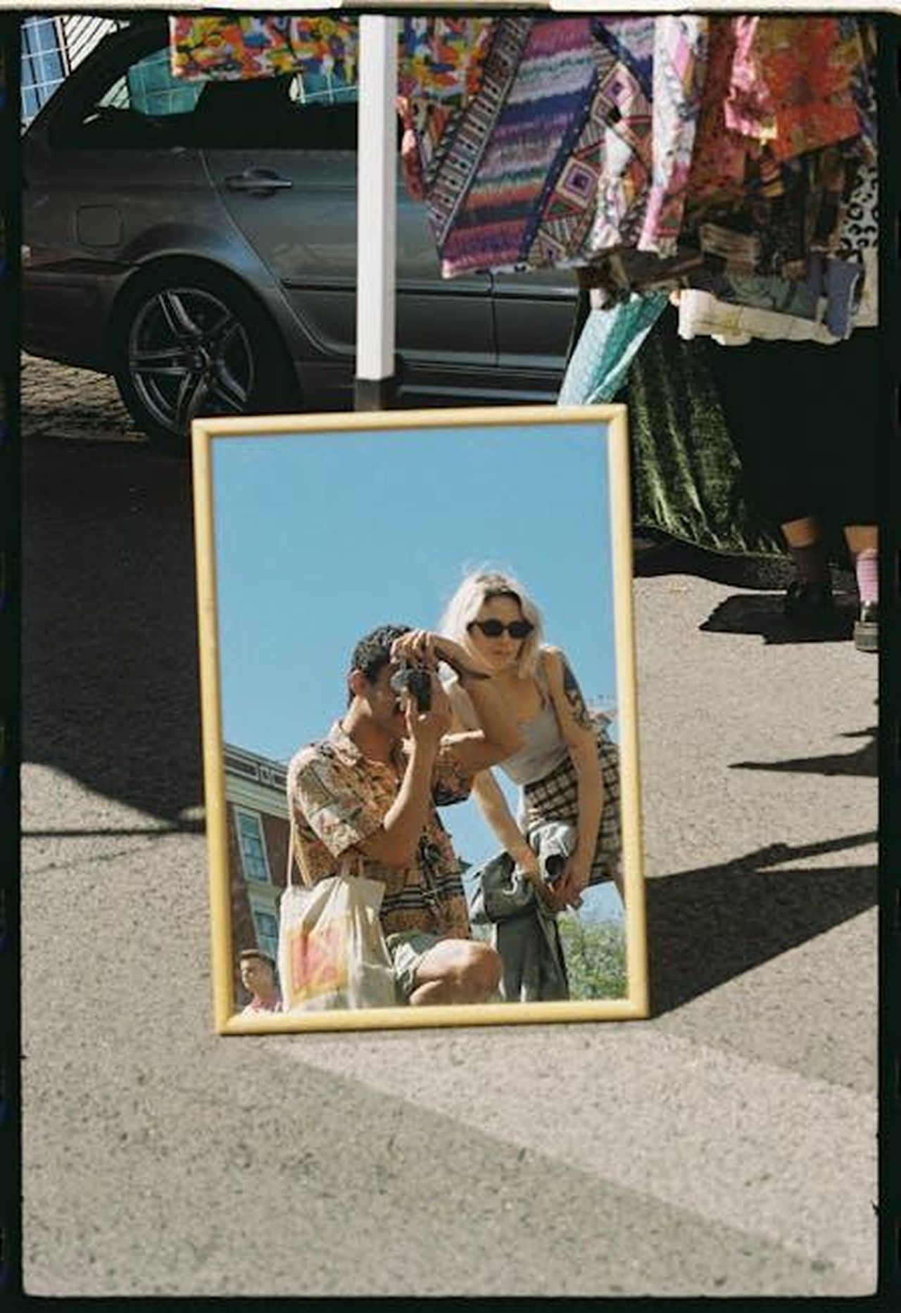 Cosa_significa_per_il_mercato_del_carsharing_nel_Regno_Unito_Cm2iWUzlfB - Veicoli24 Source: Efe Ersoy - pexels - A couple taking photos reflected in a mirror at an outdoor Lisbon market showcasing vibrant summer fashion.