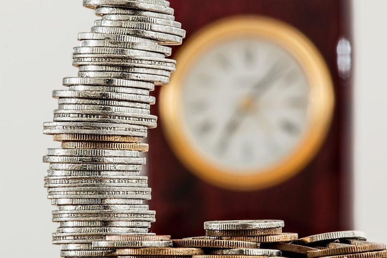 Costi_elevati_per_i_proprietari_Wzo8mK1D1e - Veicoli24 Source: Pixabay - pexels - A close-up image of stacked coins with a blurred clock, symbolizing time and money relationship.
