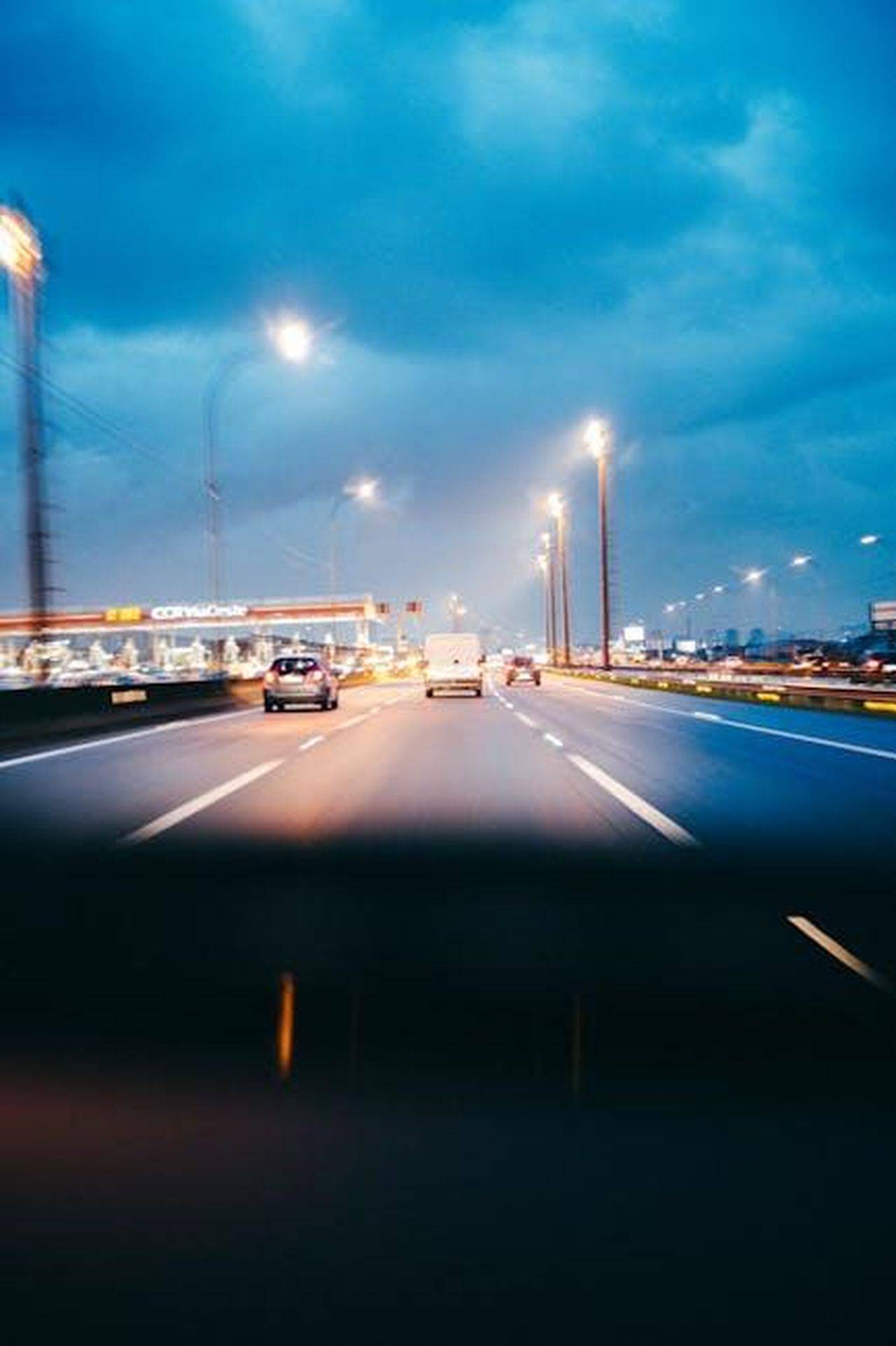 Costi_elevati_per_i_veicoli_elettrici_AkyQuyvxj9 - Veicoli24 Source: JULIO NERY - pexels - Blurred view of a busy highway at night with city lights illuminating the scene.