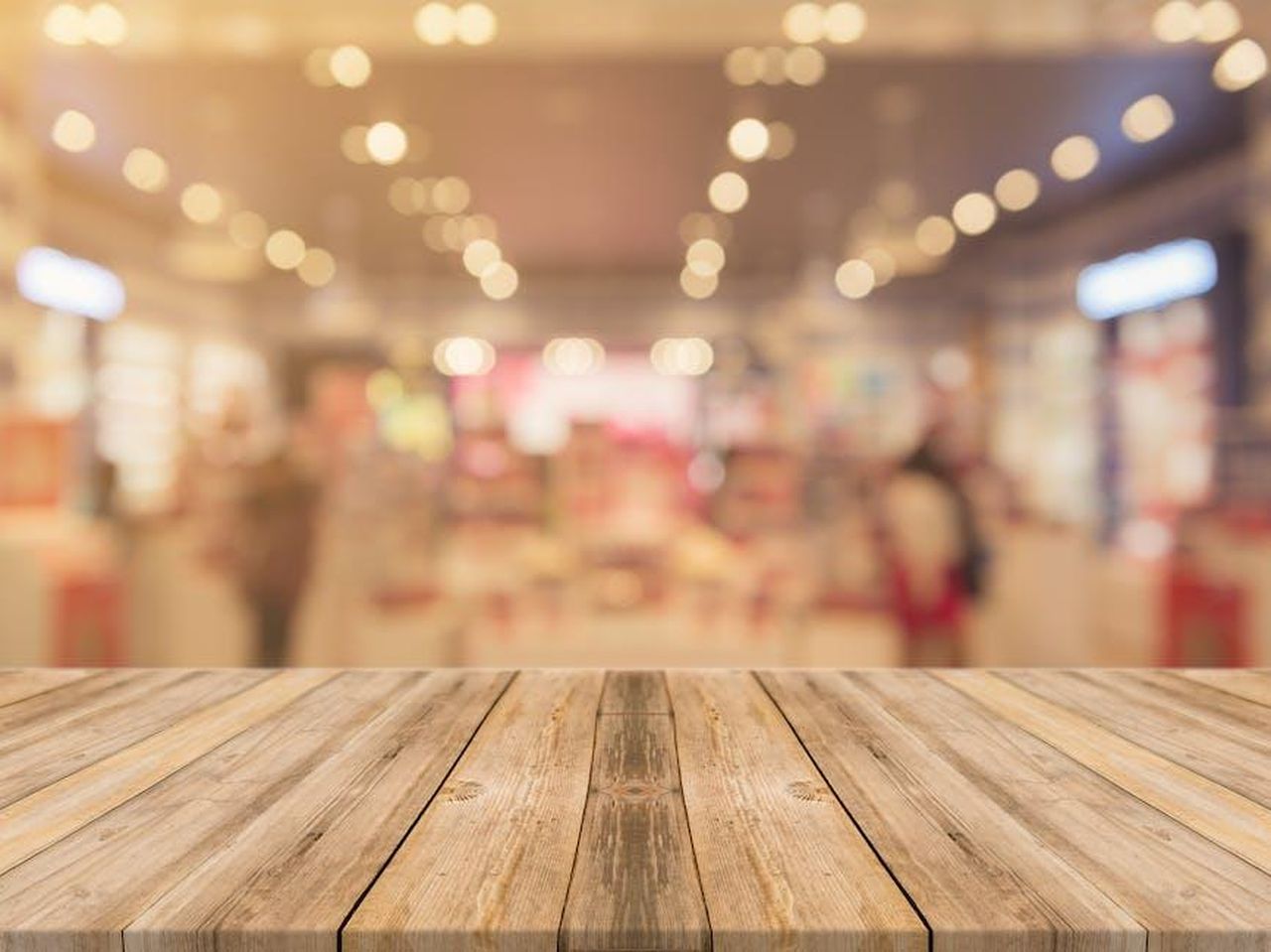 Crescita_delle_vendite_al_dettaglio_e_sfide_del_mercato_NF7USusXMK - Veicoli24 Source: Tirachard Kumtanom - pexels - Empty wooden table with blurred shopping mall background and bokeh lights.