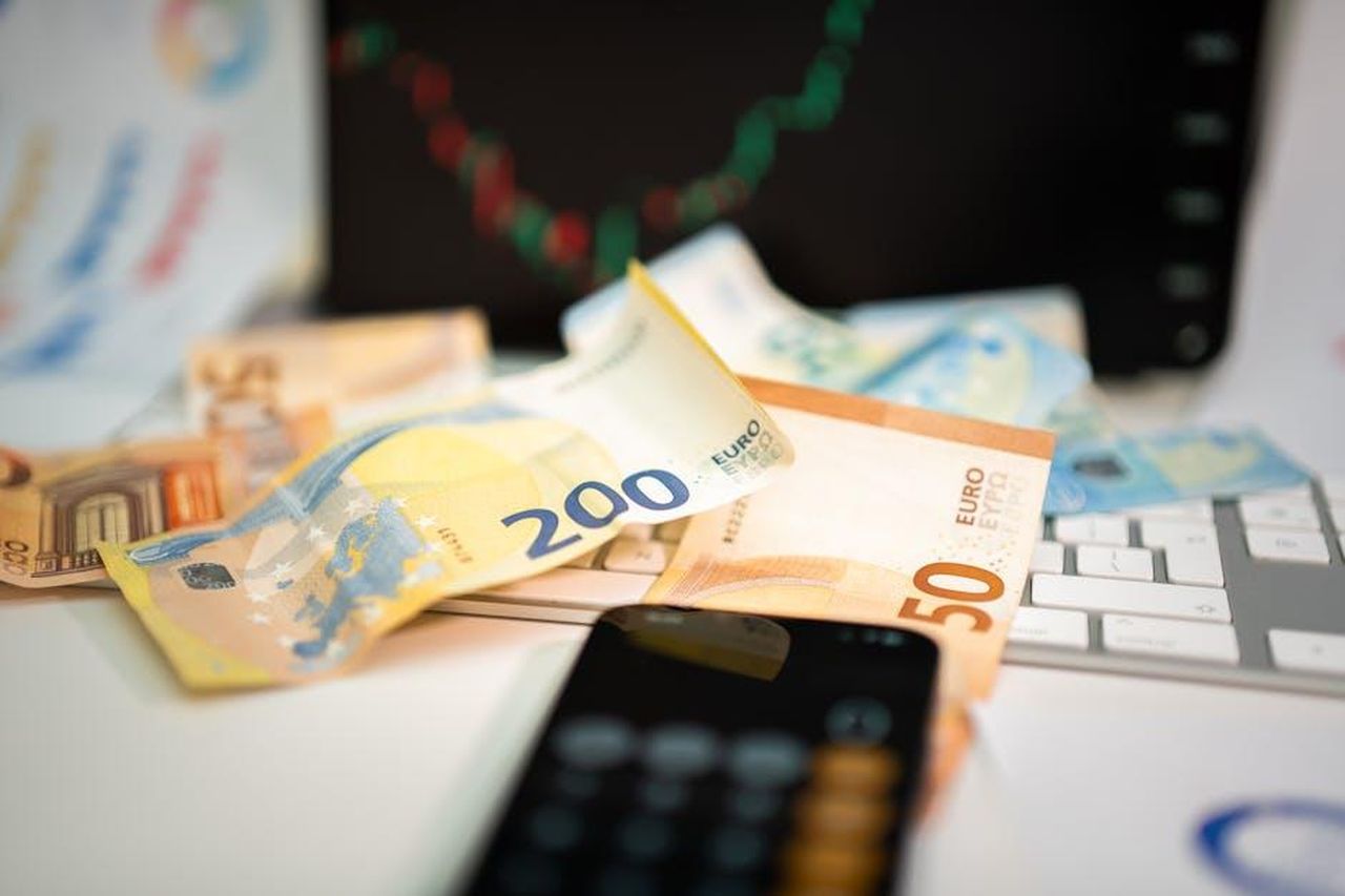 Crescita_e_declino_nei_mercati_dellUE_H8q6clzI6n - Veicoli24 Source: Jakub Zerdzicki - pexels - Euro banknotes and smartphone on desk, symbolizing finance and technology in business.