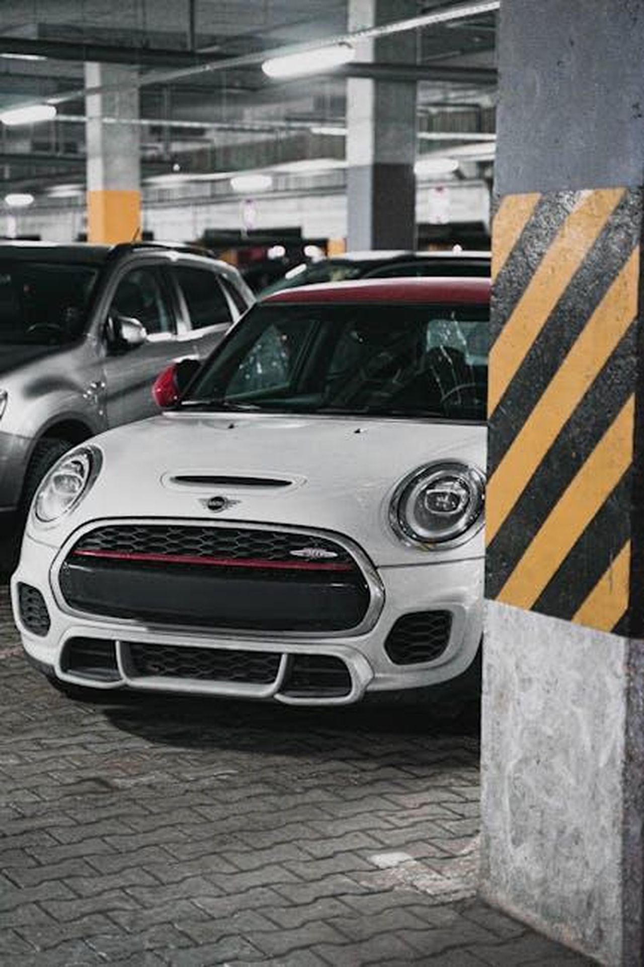 Dati_tecnici_della_MINI_Cooper_Electric_edqvW91Uth - Veicoli24 Source: Alex Urezkov - pexels - A white Mini Cooper parked in a dimly lit urban underground garage.
