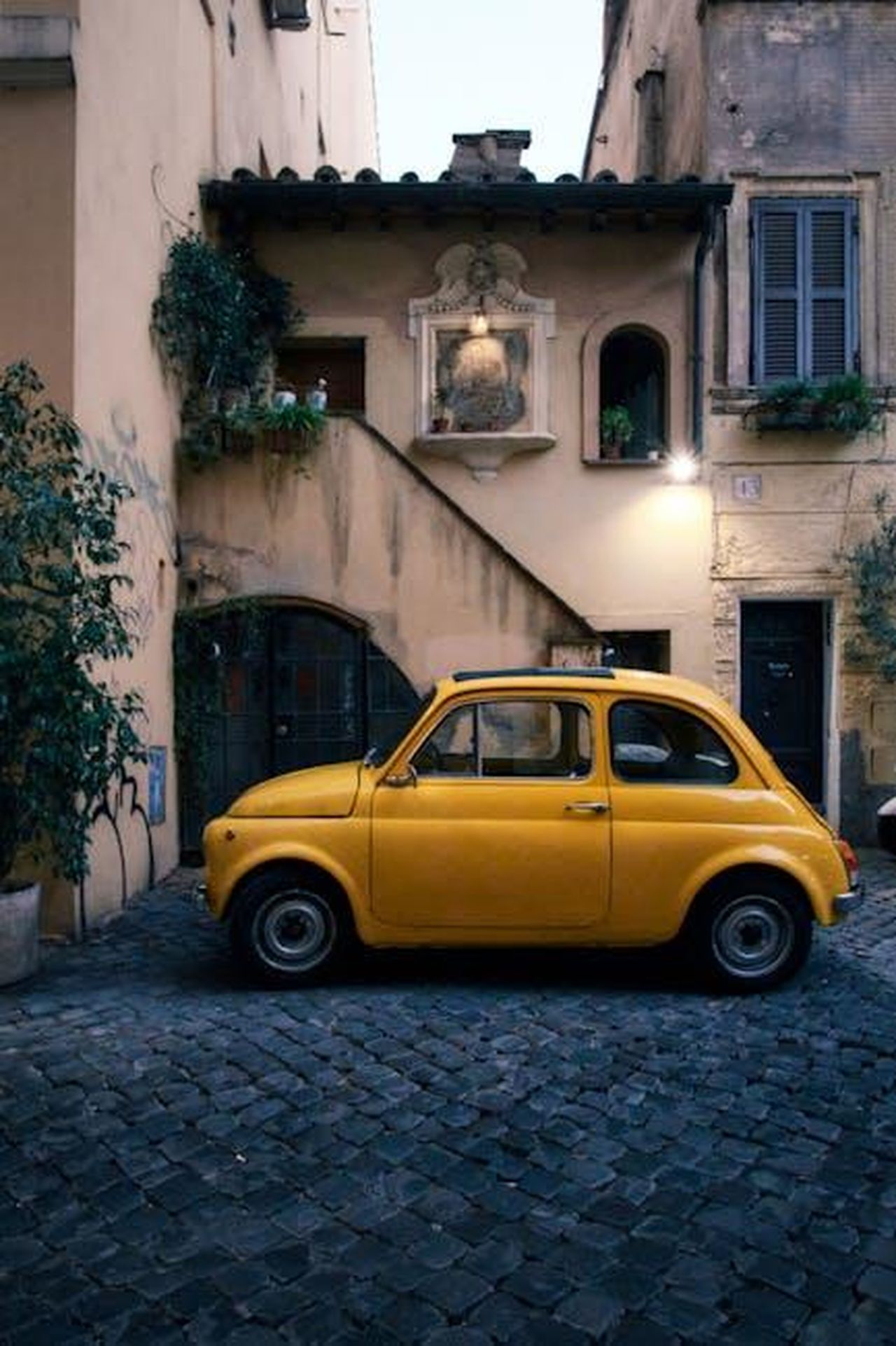 Dettagli_sul_tour_e_informazioni_aggiuntive_qtbpCGceB9 - Veicoli24 Source: Guillermo Meza - pexels - Discover the charm of Rome's streets with this classic yellow car parked by a rustic building.