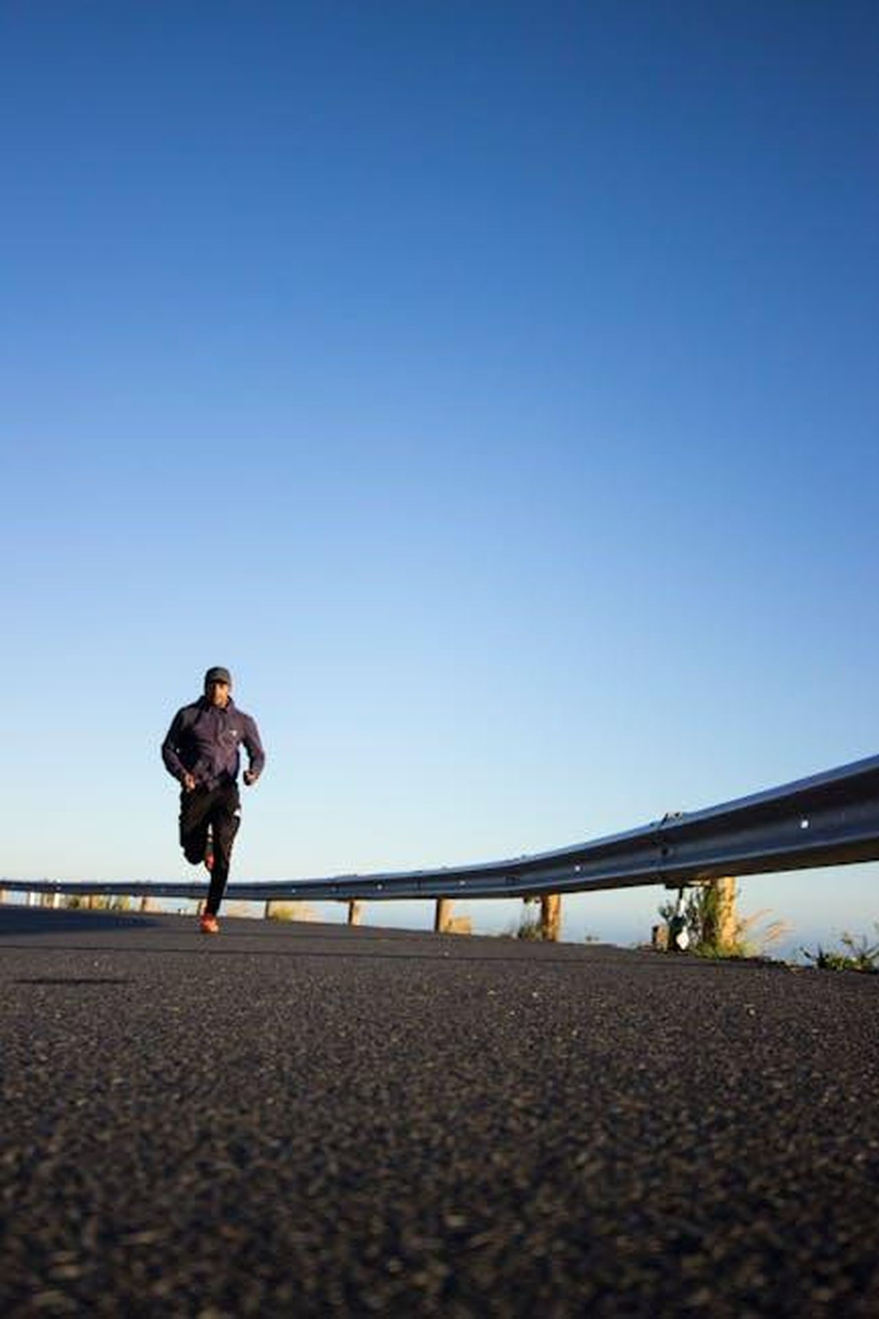 Dettagli_sulla_gara_orari_e_aspettative_h1mr7RC1gN - Veicoli24 Source: Tembela Bohle - pexels - An athletic man jogging on an open road with a clear blue sky in Cape Town, South Africa.