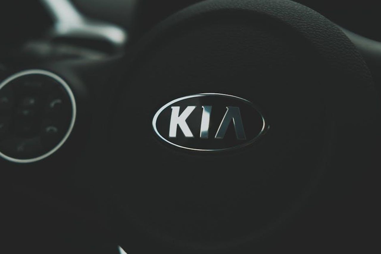 Dettagli_sulla_piattaforma_e_sullinterno_dellEV4_HJfr40JbXk - Veicoli24 Source: Connor McManus - pexels - Focus on the sleek Kia logo on a steering wheel, highlighting automotive design.