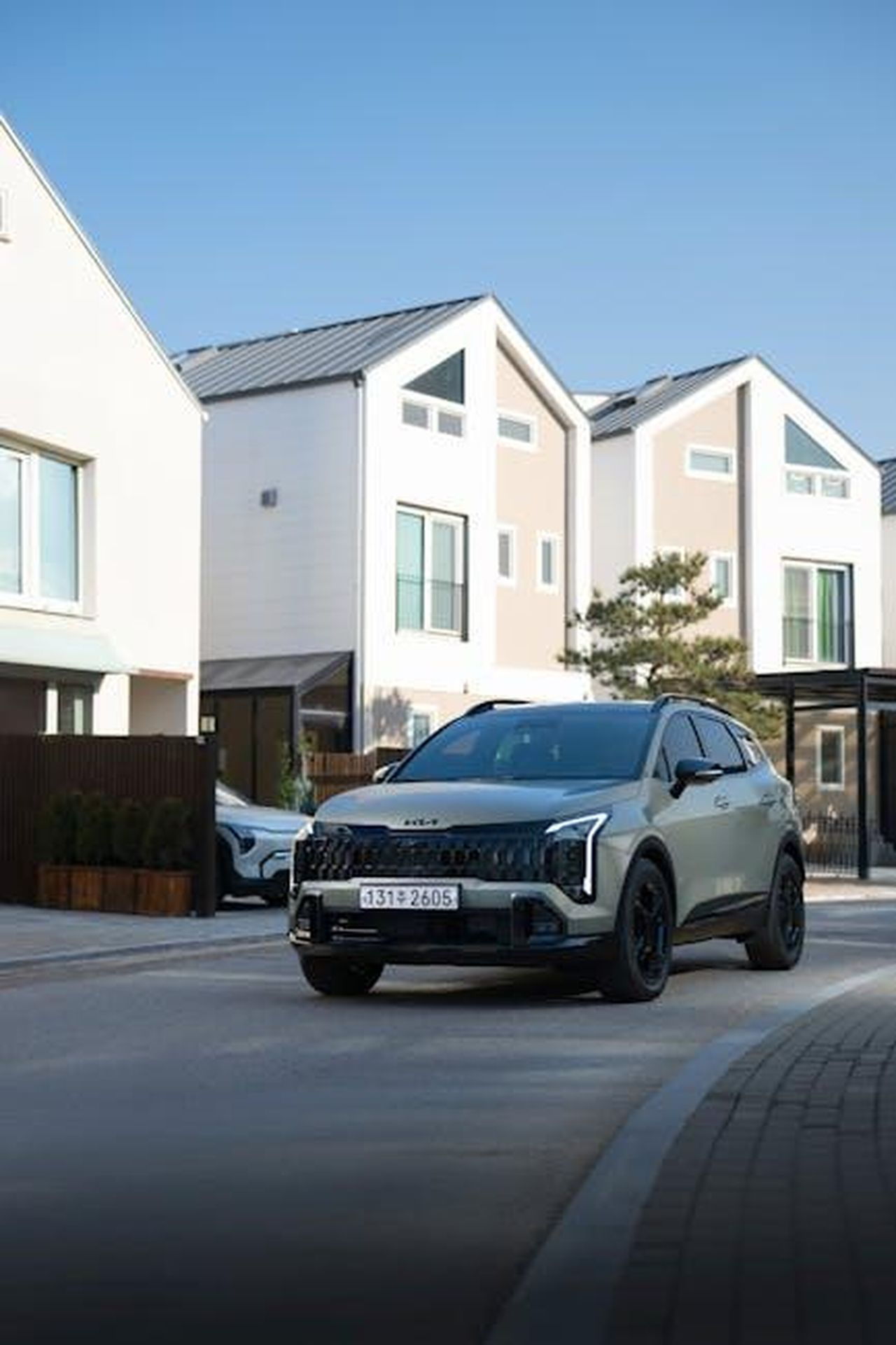Dimensioni_e_capacit_del_Kia_PV5_4Ot3cV8aoi - Veicoli24 Source: Hyundai Motor Group - pexels - Stylish SUV parked in a suburban area with modern houses in the background.
