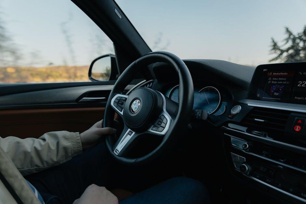 Dinamiche_di_guida_di_alta_classe_e_efficienza_aumentata_hLIp9xaAv9 - Veicoli24 Source: Aleksandar Andreev - pexels - Close-up of a person driving a BMW showcasing the modern car interior during the day.