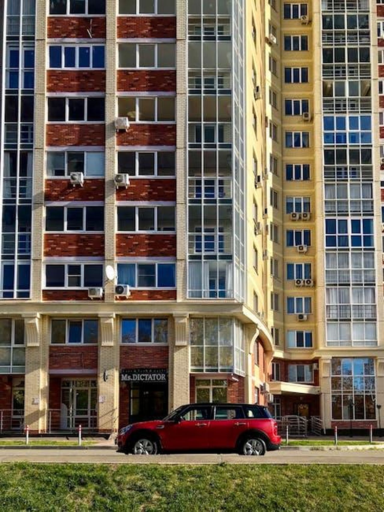 Disponibilit_dellEdizione_Oxford_ODYhKXQ6fX - Veicoli24 Source: Лев Рогожников - pexels - Vertical shot of high-rise apartment buildings with a red Mini Cooper parked in front.