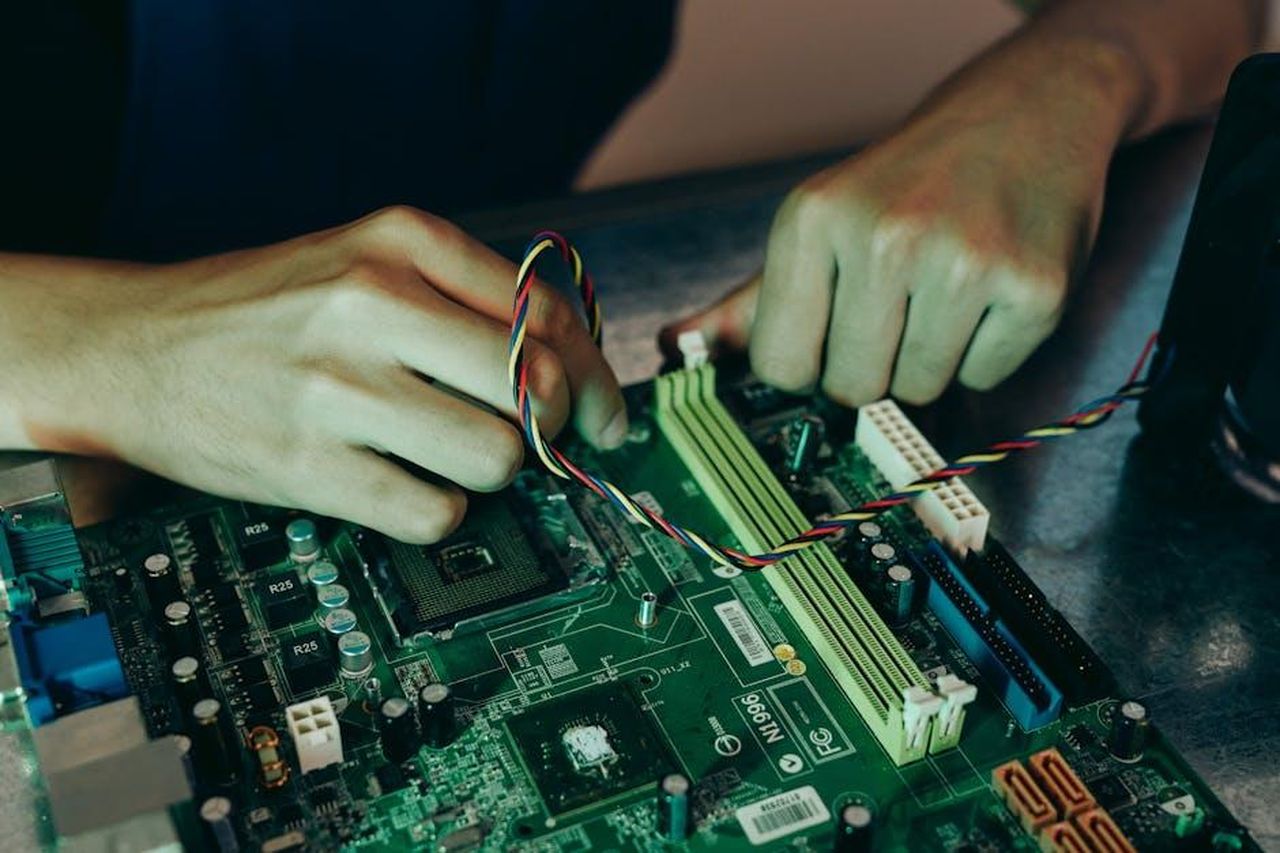 Dove_viene_prodotta_la_Ram_1500_BtKMXf19tj - Veicoli24 Source: Mikhail Nilov - pexels - Person assembling computer motherboard with colorful wires, showcasing technology and engineering.