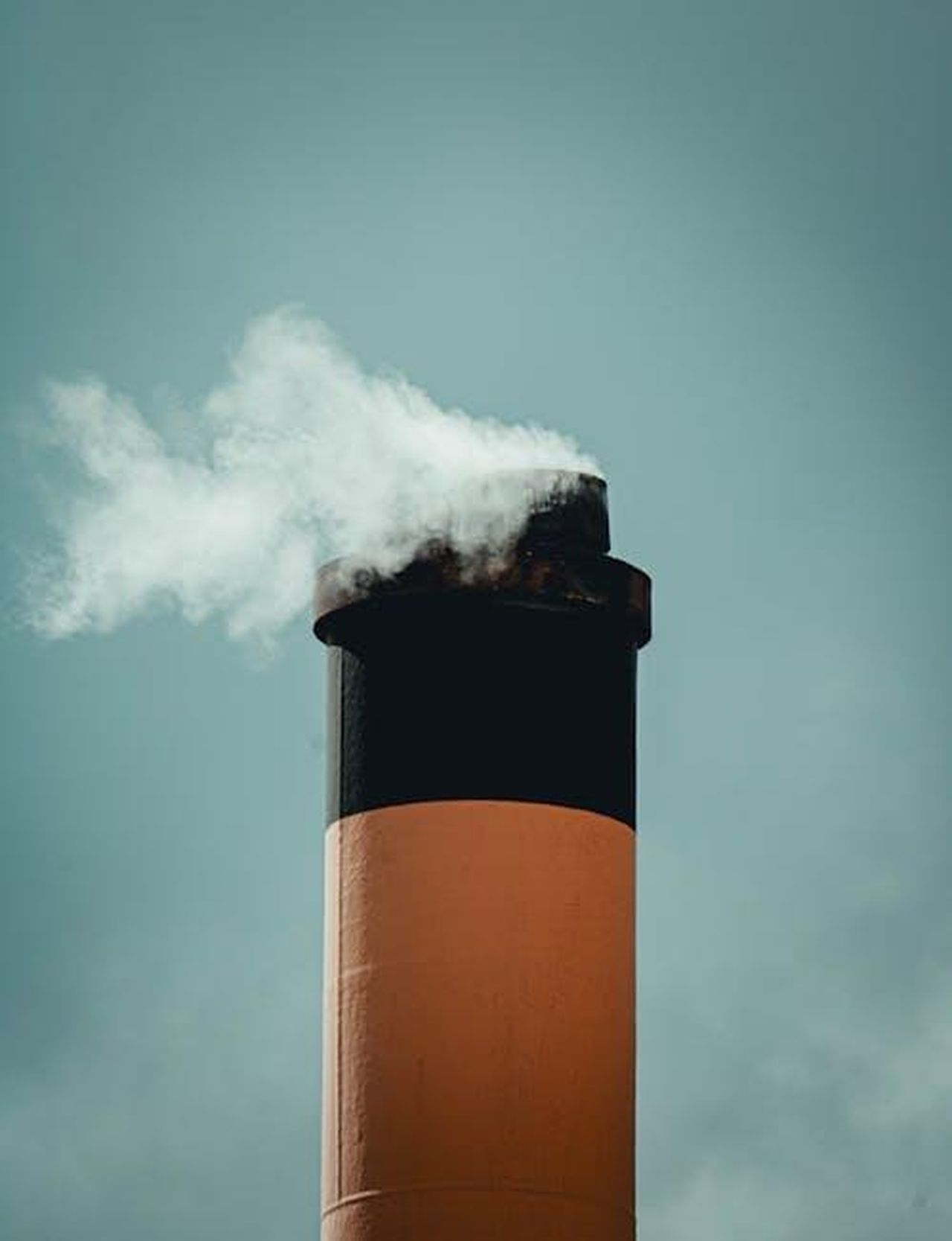 Emissioni_CO2_e_Consumo_wiaJ7hLHw2 - Veicoli24 Source: Tony Mrst - pexels - A tall industrial chimney emits smoke into the sky, symbolizing air pollution.