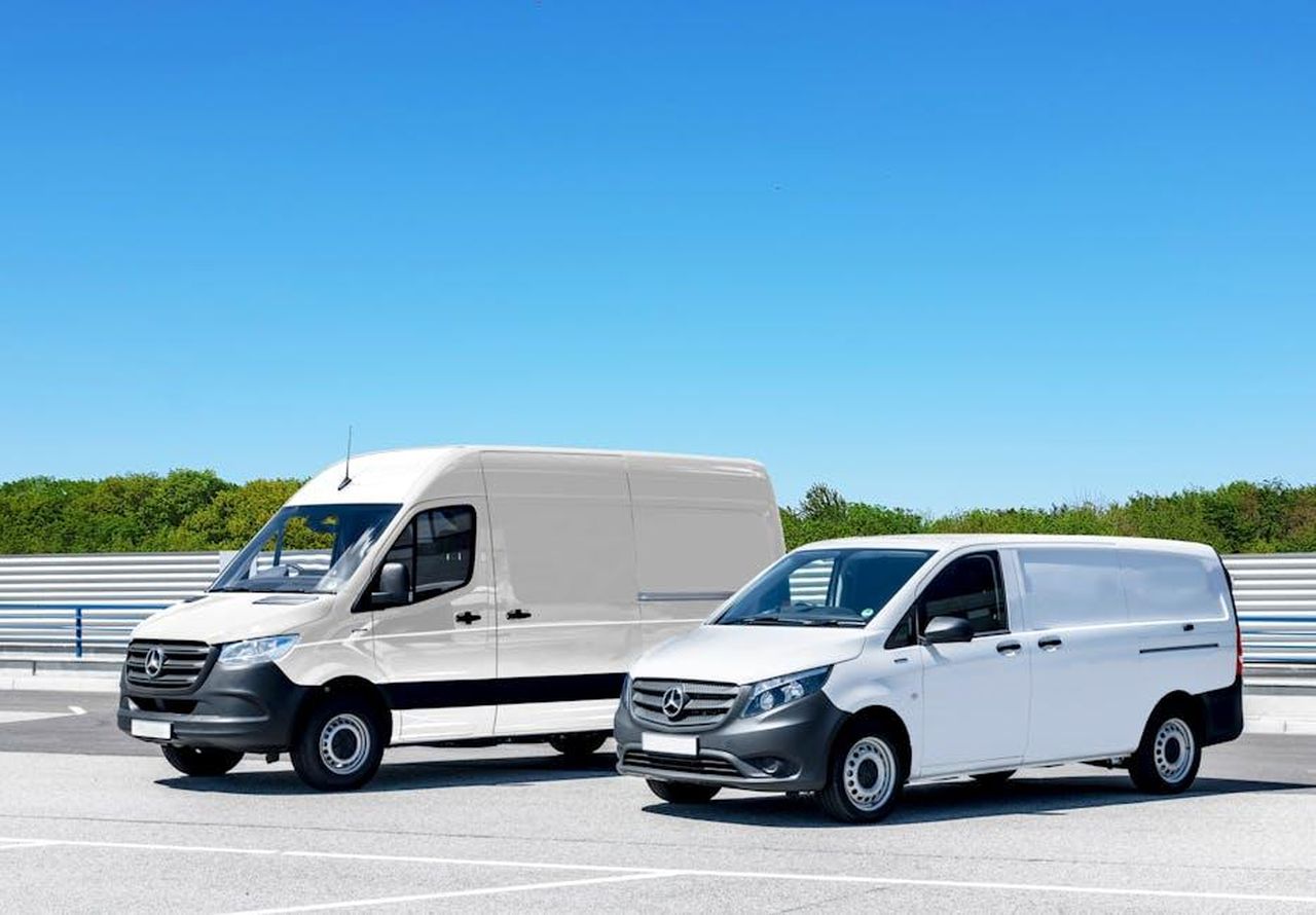 Evoluzione_dei_piani_di_MercedesBenz_per_i_furgoni_elettrici_WiN28Pz3iz - Veicoli24 Source: Bernard Foss - pexels - Two white delivery vans parked in a spacious parking lot under a clear blue sky.