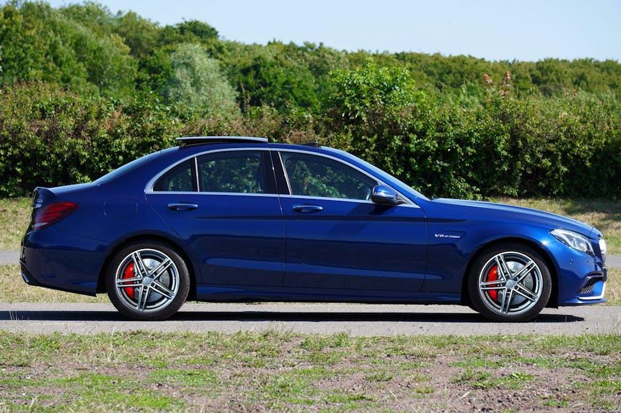 Evoluzione_del_motore_V8_attuale_T2lH4yPucA - Veicoli24 Source: Mike Bird - pexels - A sleek blue luxury sedan parked on a rural road surrounded by greenery.
