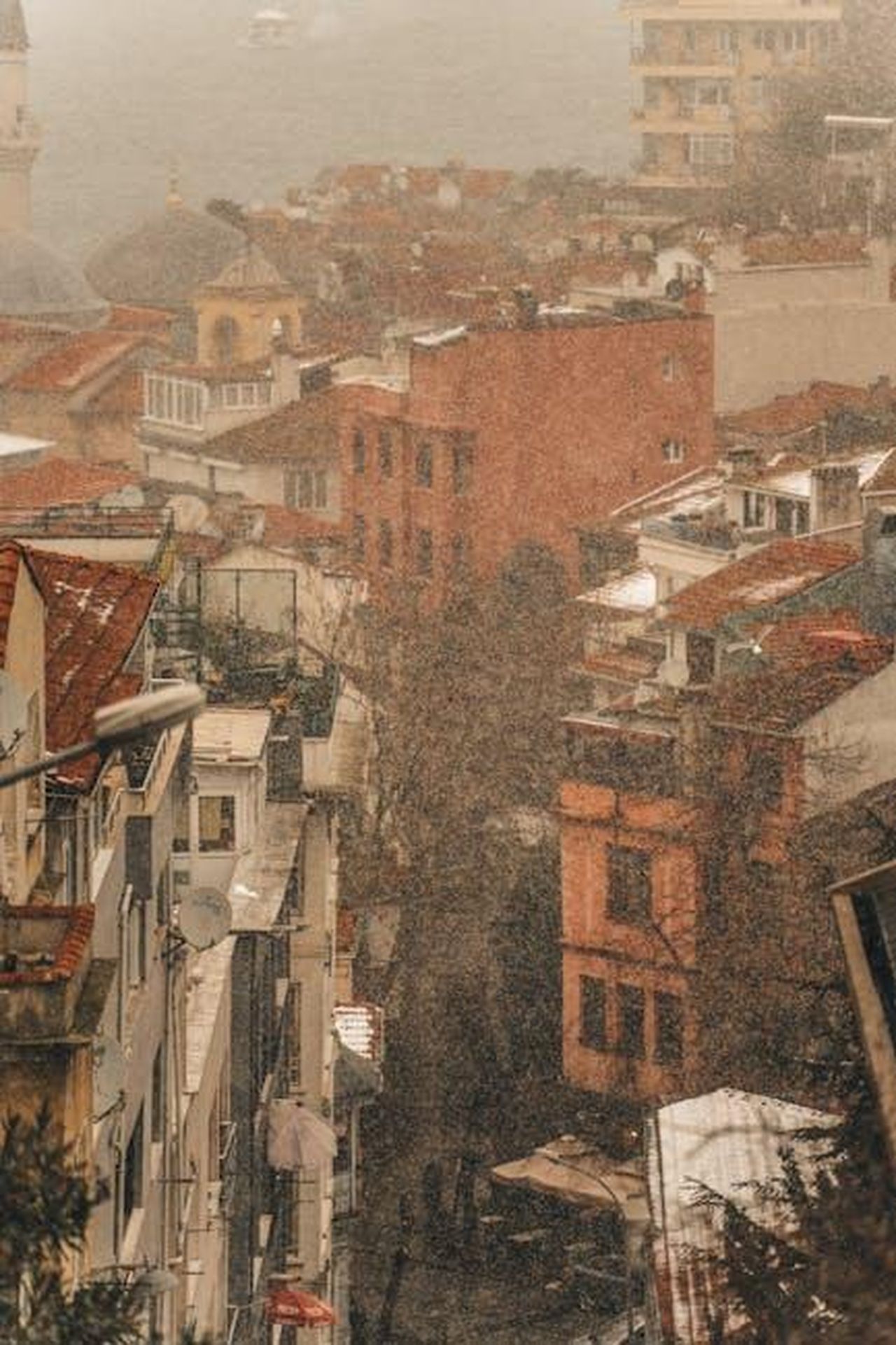 Fattori_che_influenzano_la_criminalit_veicolare_ZKHZ93kbj0 - Veicoli24 Source: Gökhan Çınar - pexels - A foggy view of Istanbul's urban landscape with red rooftops and historical architecture.