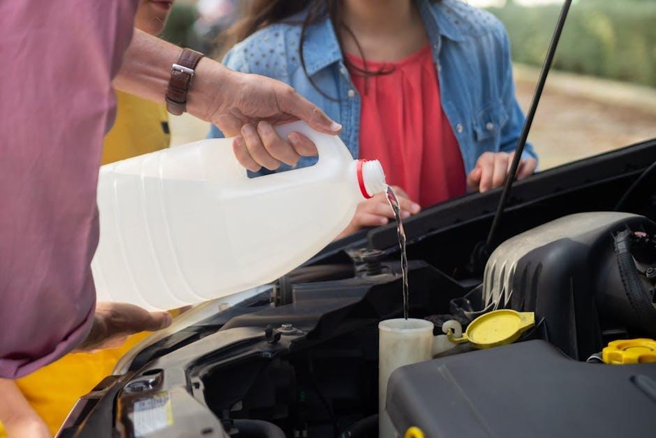 Focus_su_efficienza_e_aerodinamica_qkaZ6WHC2x - Veicoli24 Source: Kampus Production - pexels - Close-up of a person pouring windshield washer fluid into a car, emphasizing vehicle maintenance.