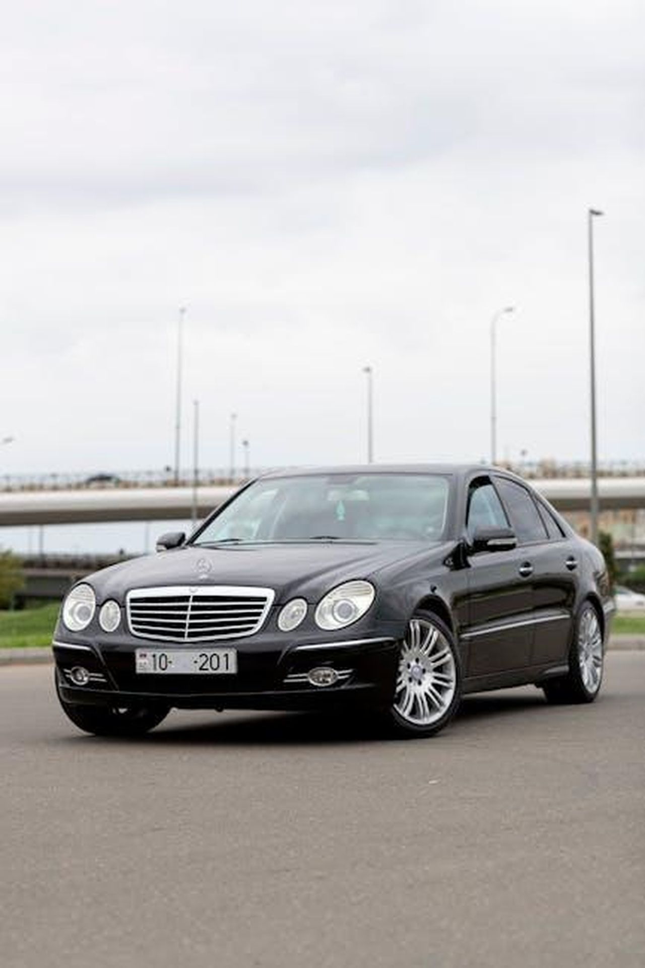 Futuro_dei_motori_V8_e_V12_mo5xwH042K - Veicoli24 Source: Karim - pexels - A stylish black Mercedes-Benz sedan parked on a roadside under a cloudy sky.