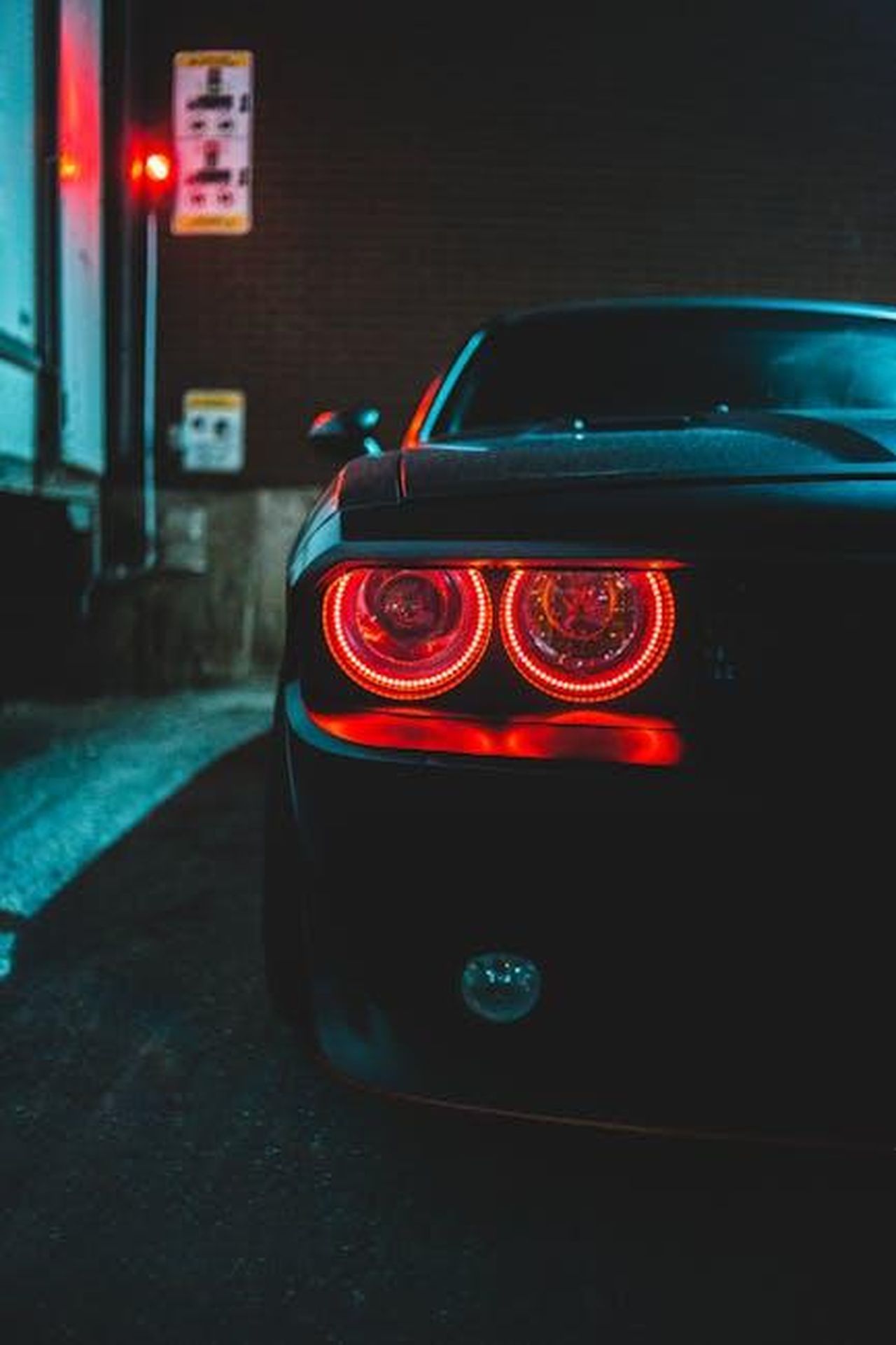 Futuro_elettrico_di_RollsRoyce_TgrLIKNQ4X - Veicoli24 Source: Erik Mclean - pexels - Close-up of a luxury sports car with glowing taillights parked in a city alley.