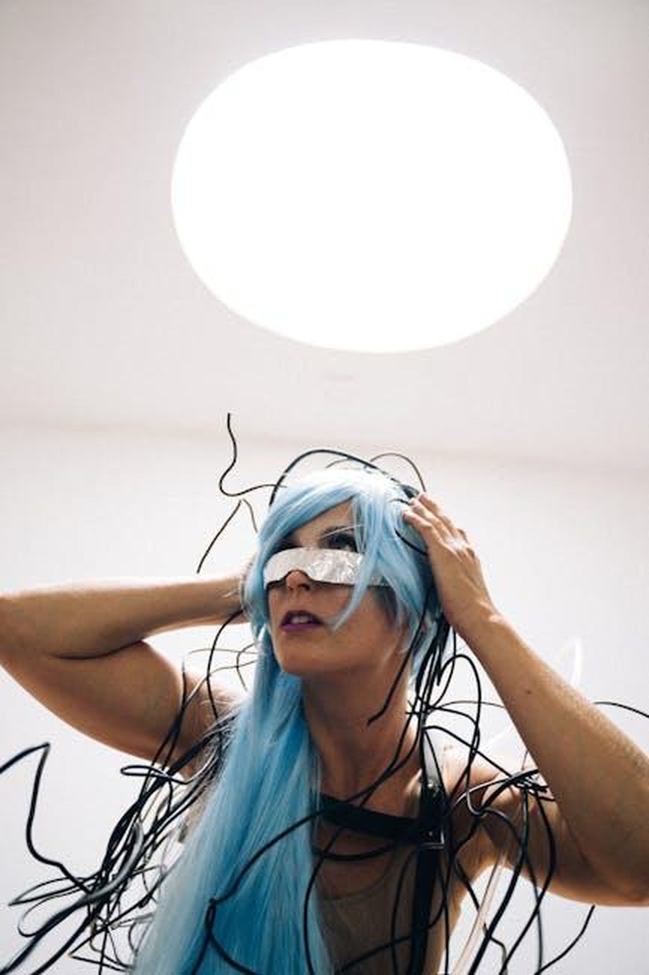 Il_futuro_della_moda_e_dellauto_ZL8nYDtkVC - Veicoli24 Source: Anna Tarazevich - pexels - A futuristic woman in a cyberpunk style with a blue wig and wires, evoking a high-tech vibe.