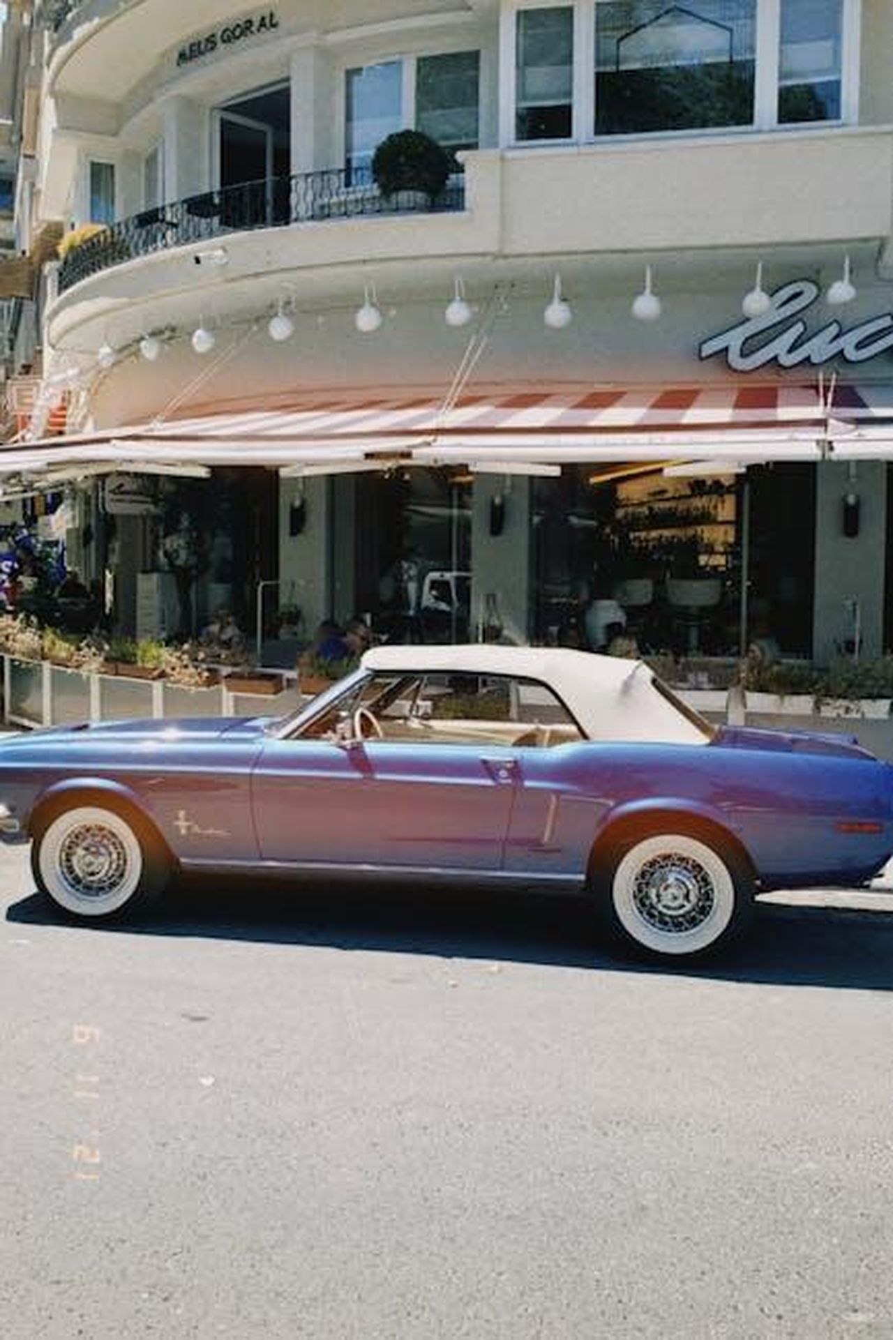 Il_possibile_ritorno_della_Mustang_Boss_nella_lineup_attuale_rZ2ACQHGBe - Veicoli24 Source: Ece Tunçkol - pexels - Classic blue Mustang convertible parked on city street outside a cafe.