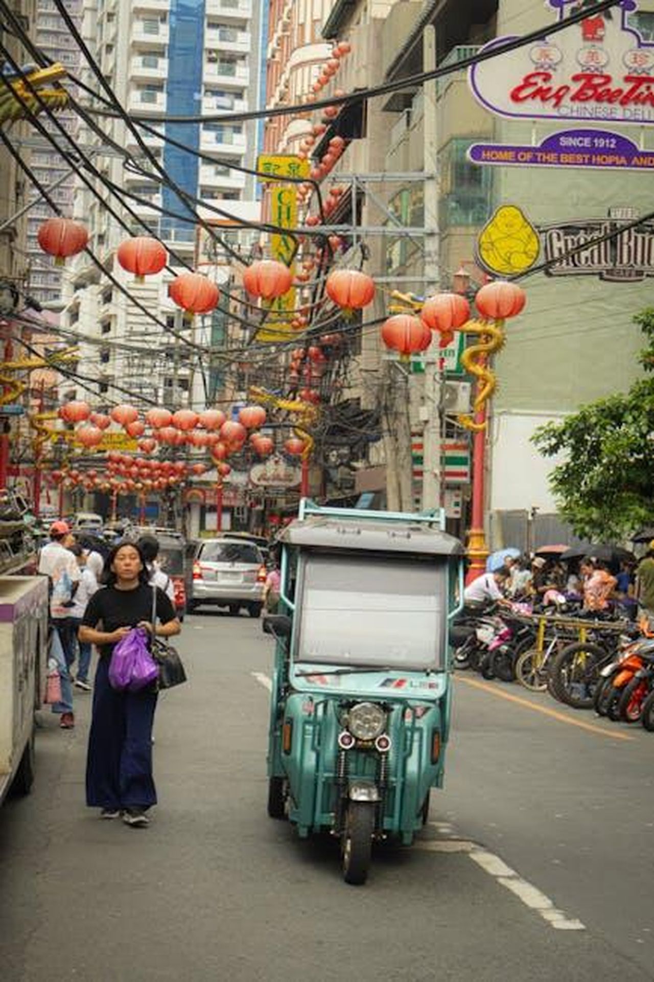 Impatto_del_mercato_cinese_sulla_crescita_cNWiRNCcue - Veicoli24 Source: Justine Ross Cruz - pexels - A bustling urban street with lanterns, people, and vehicles showcasing a vibrant Asian market atmosphere.