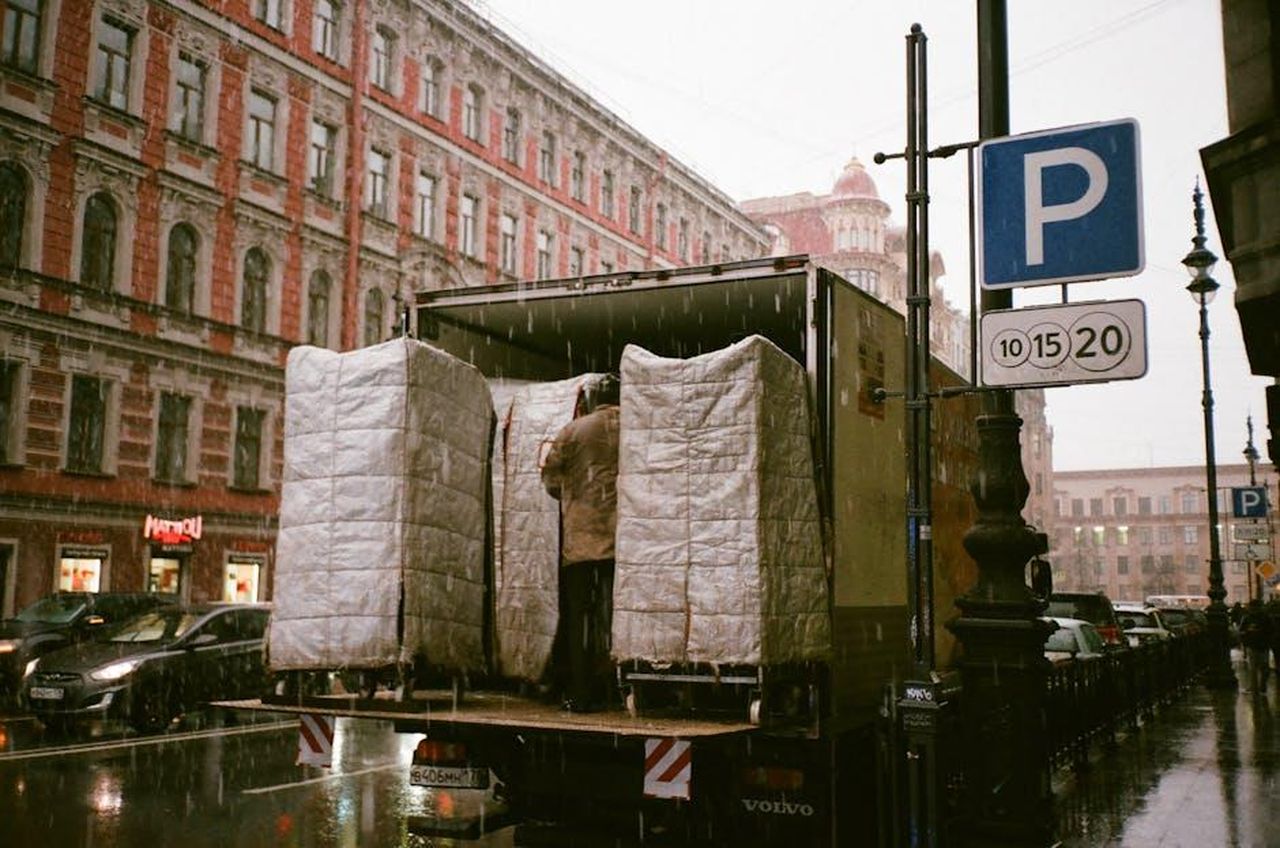 Impatto_del_richiamo_sui_proprietari_di_Volvo_EX90_25JOY1RFMf - Veicoli24 Source: Darya Sannikova - pexels - A truck being loaded on a rainy urban street, reflecting city life and transportation.