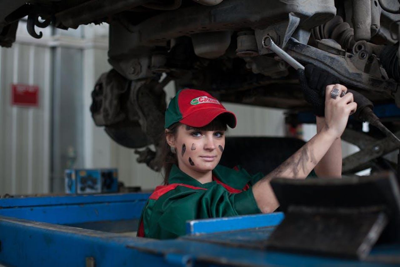 Impatto_sui_produttori_americani_LJpLgtJUhr - Veicoli24 Source: Pixabay - pexels - Female mechanic maintaining a car in an auto repair shop, showcasing skill and concentration.