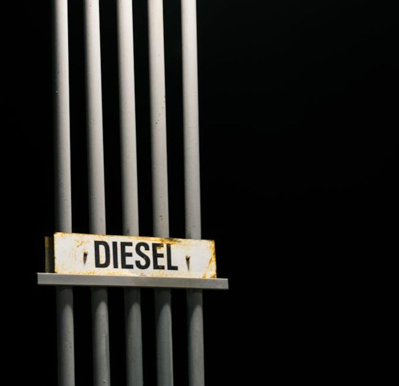 Impegno_per_i_motori_a_combustione_QXYkLD15ft - Veicoli24 Source: Bo Stevens - pexels - Diesel fuel sign on metal pipes against a dark black background at night.