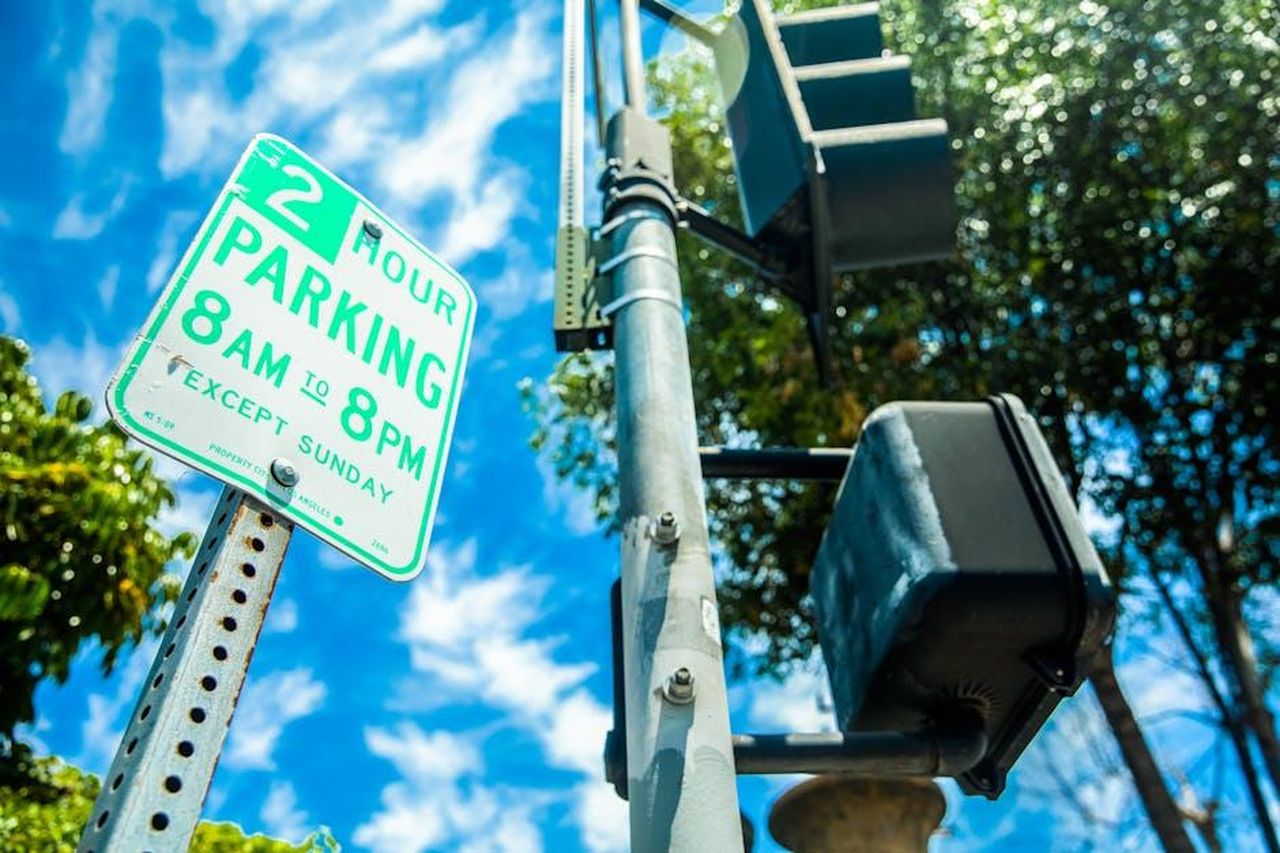 Implicazioni_globali_delle_decisioni_europee_xCb61vpQgL - Veicoli24 Source: Ekaterina Belinskaya - pexels - Close-up of a parking sign next to a traffic light in a sunny USA street.