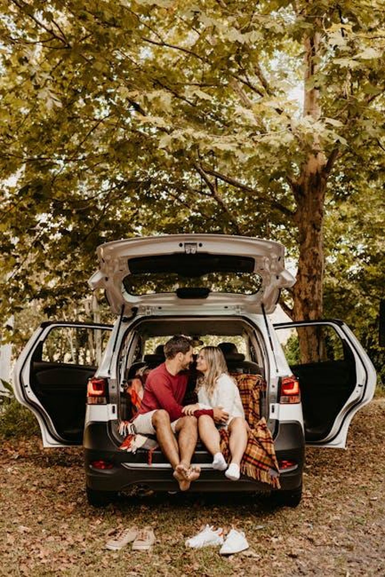 Implicazioni_per_i_fornitori_di_carsharing_nel_Regno_Unito_yJDMPvCqkT - Veicoli24 Source: Jonathan Borba - pexels - Couple sitting in the back of a car, sharing a romantic moment outdoors among lush trees.